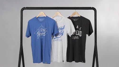 a heather blue, white, and black tee hanging on a rack