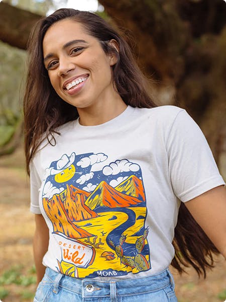 women wearing a white tee with an illustration of mountain and river scene printed on it