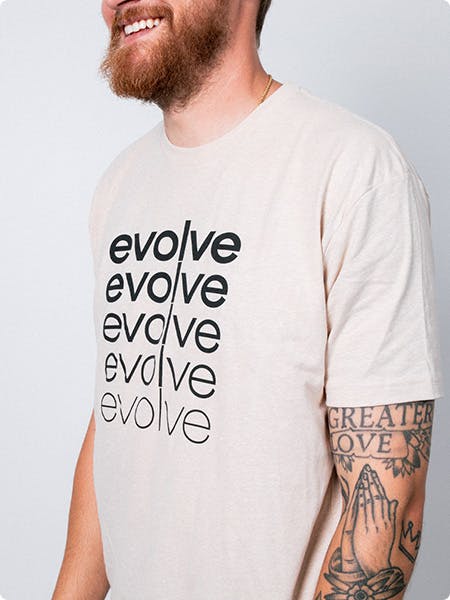 man wearing a bone color tee with the word evolve printed repeatably on the shirt