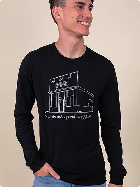 man wearing a black long sleeve tee with an illustration of a building printed on it