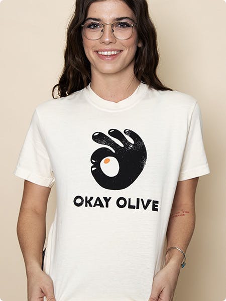 women wearing a white tee with a hand and the words okay olive printed on it