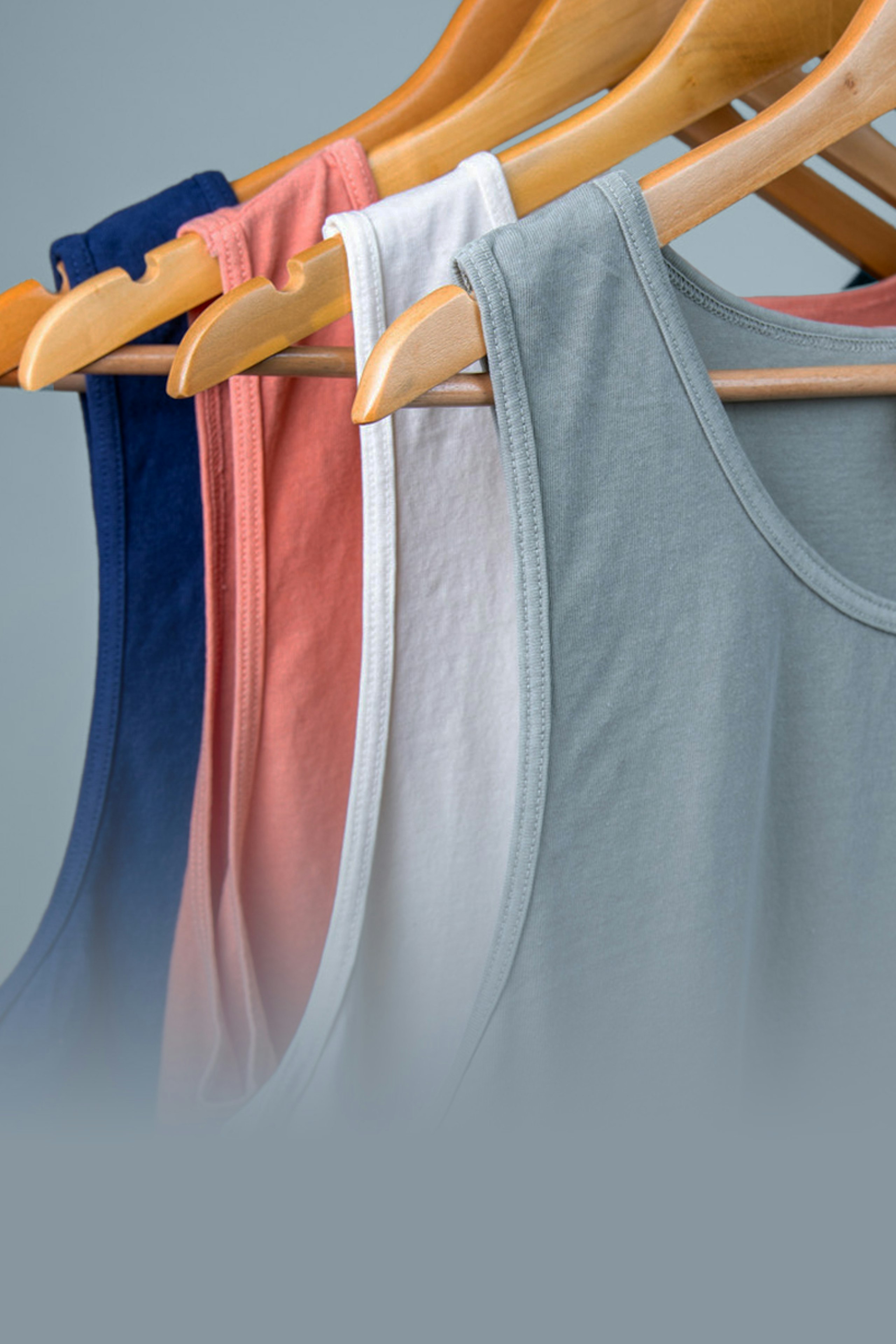 collection of tank tops hanging on hangers