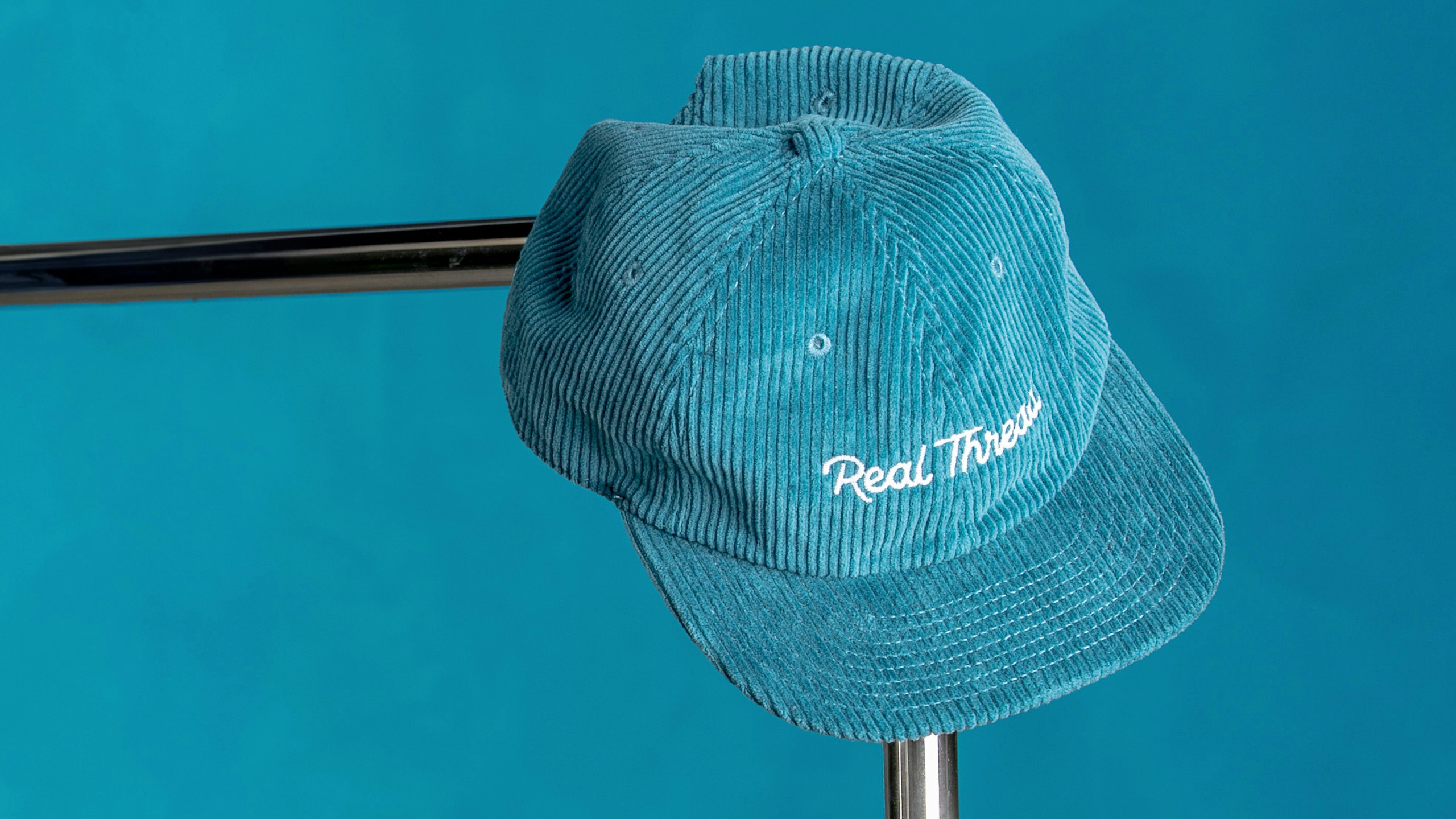 a blue corduroy hat with real thread logo embroidered on the front