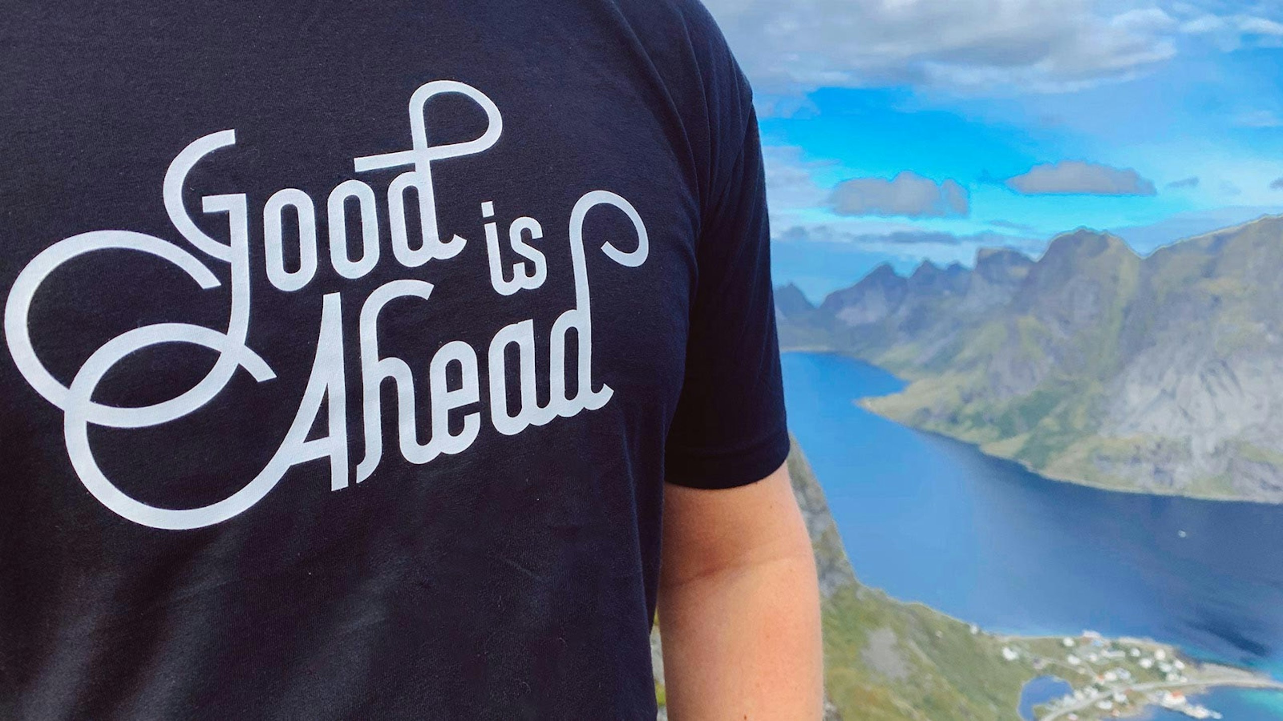 person wearing a black shirt with the words "good is ahead" printed on it in white