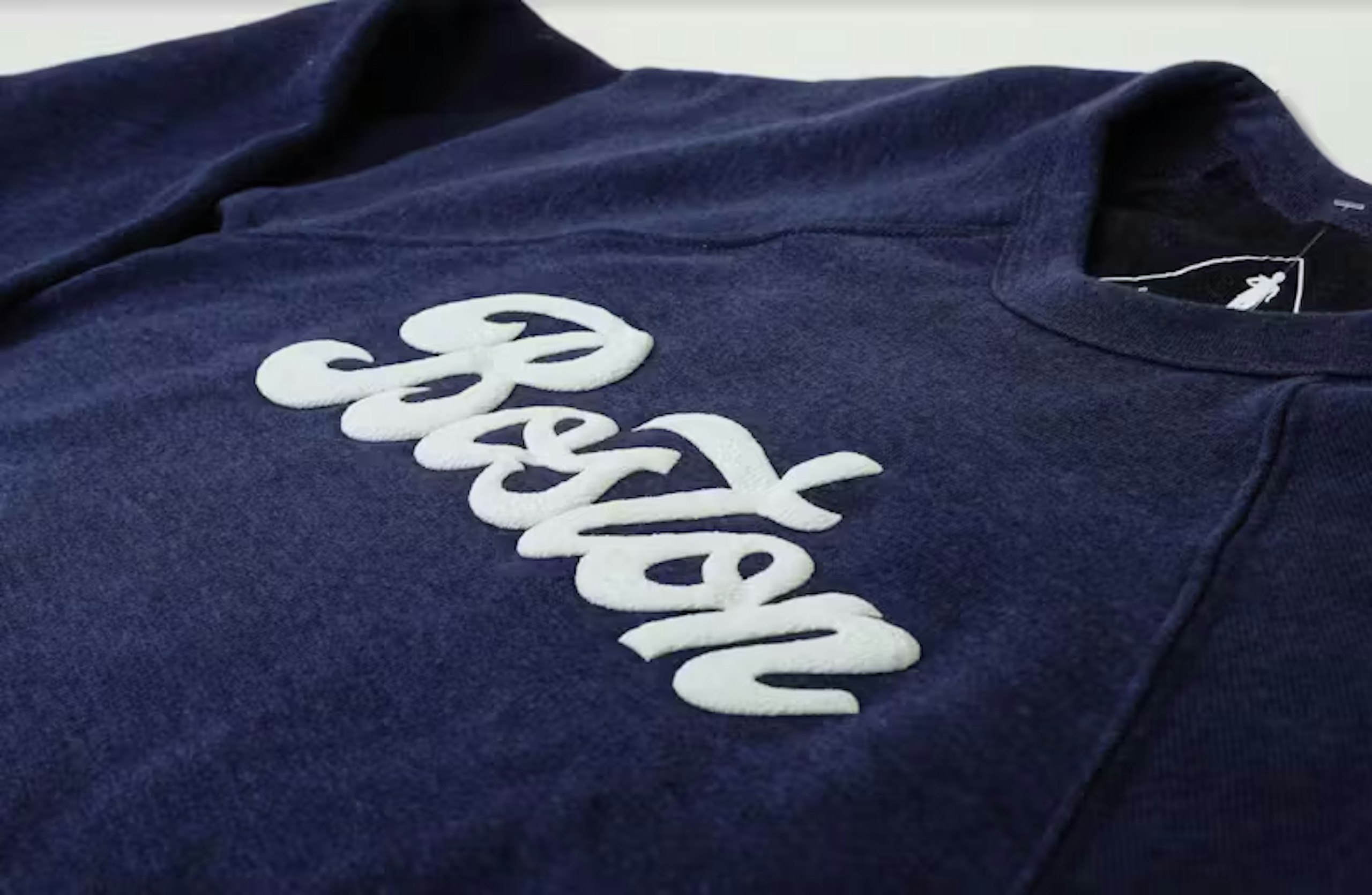 a white word "boston" printed in puff print on a navy t-shirt in a script font