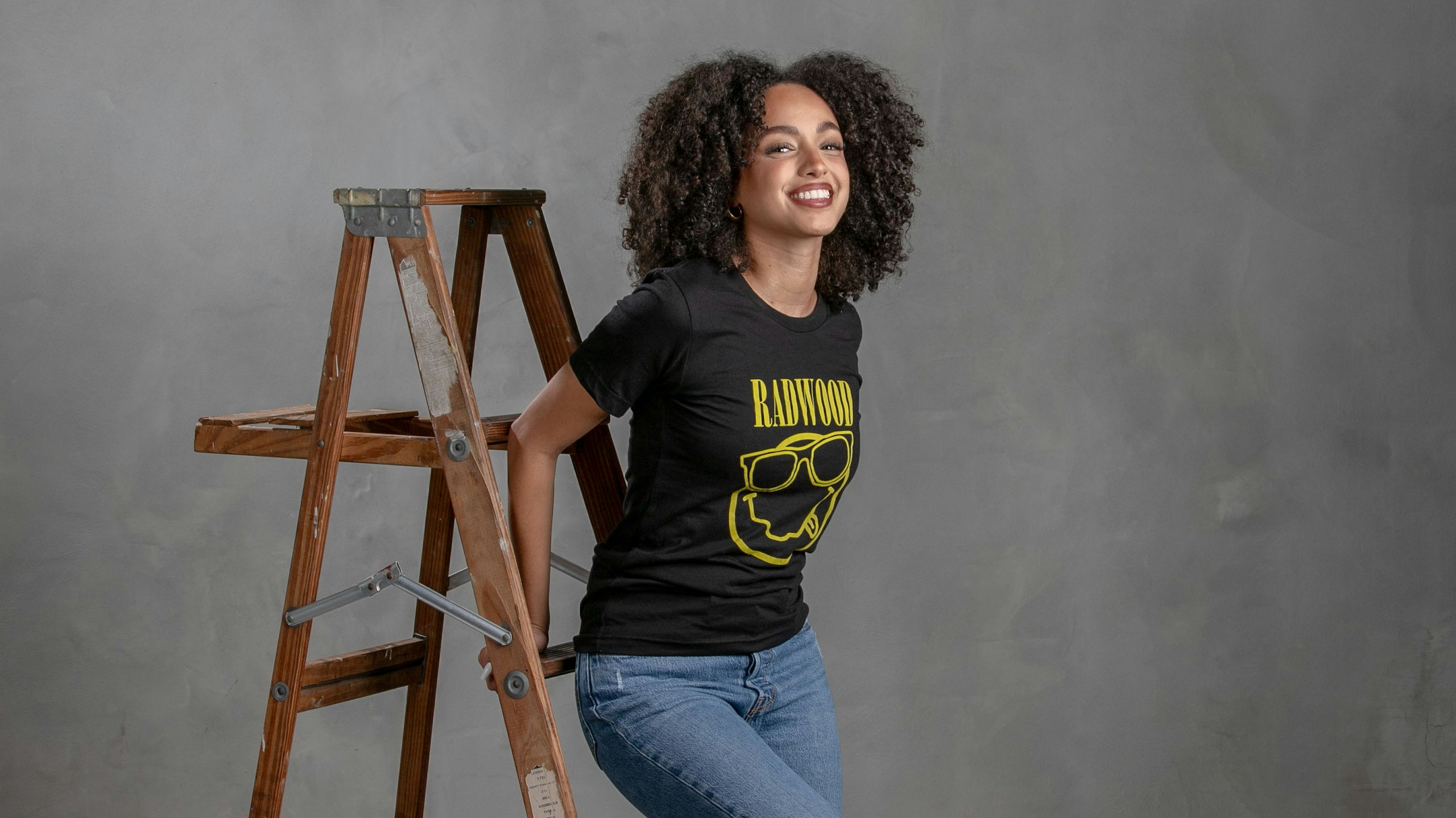 women in a black t-shirt leaning on a ladder