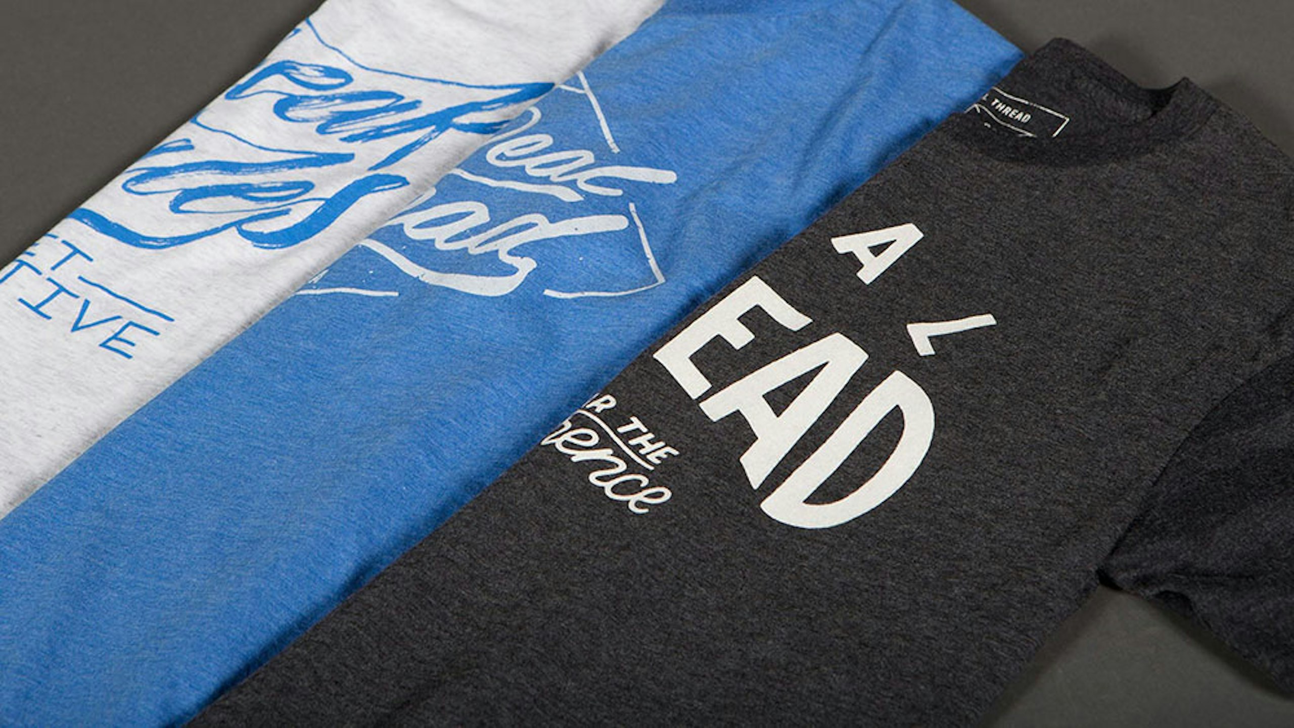 three t-shirts stacked on each other - white, blue, and black
