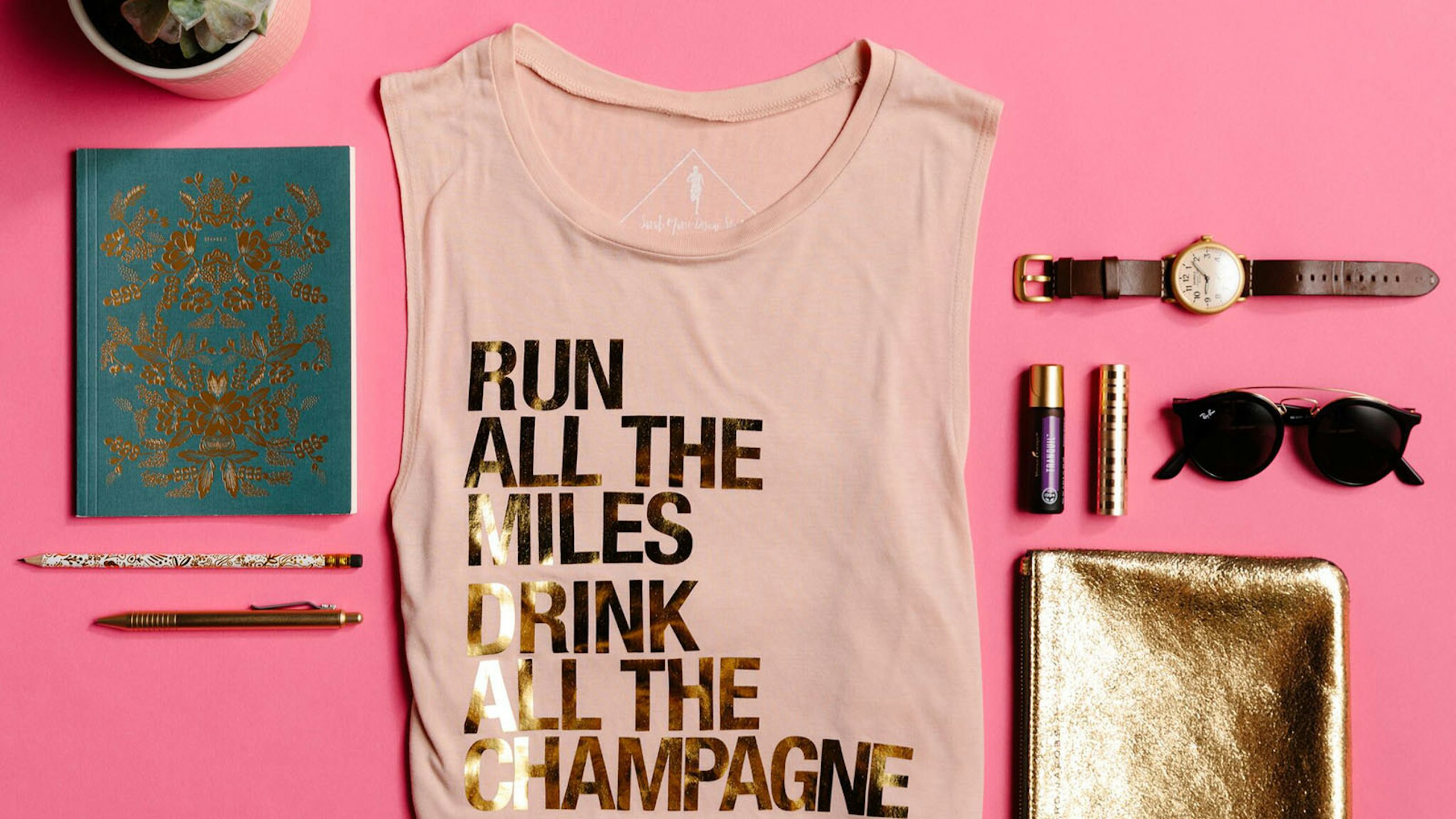 pink tank top with notebook, pens, and other assorted items on a pink background
