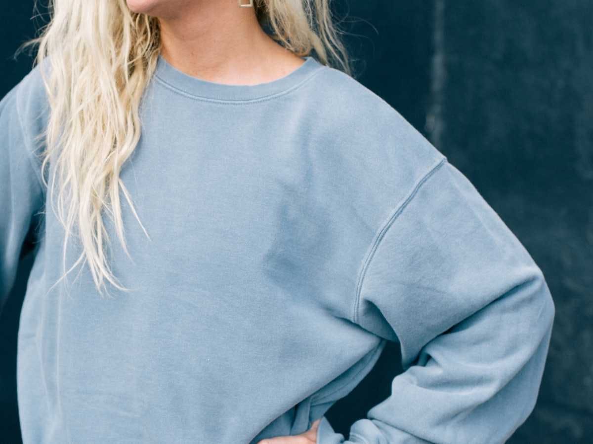 A blonde-haired girl wears a steel blue pullover sweatshirt. A blonde-haired girl wears a steel blue pullover sweatshirt.