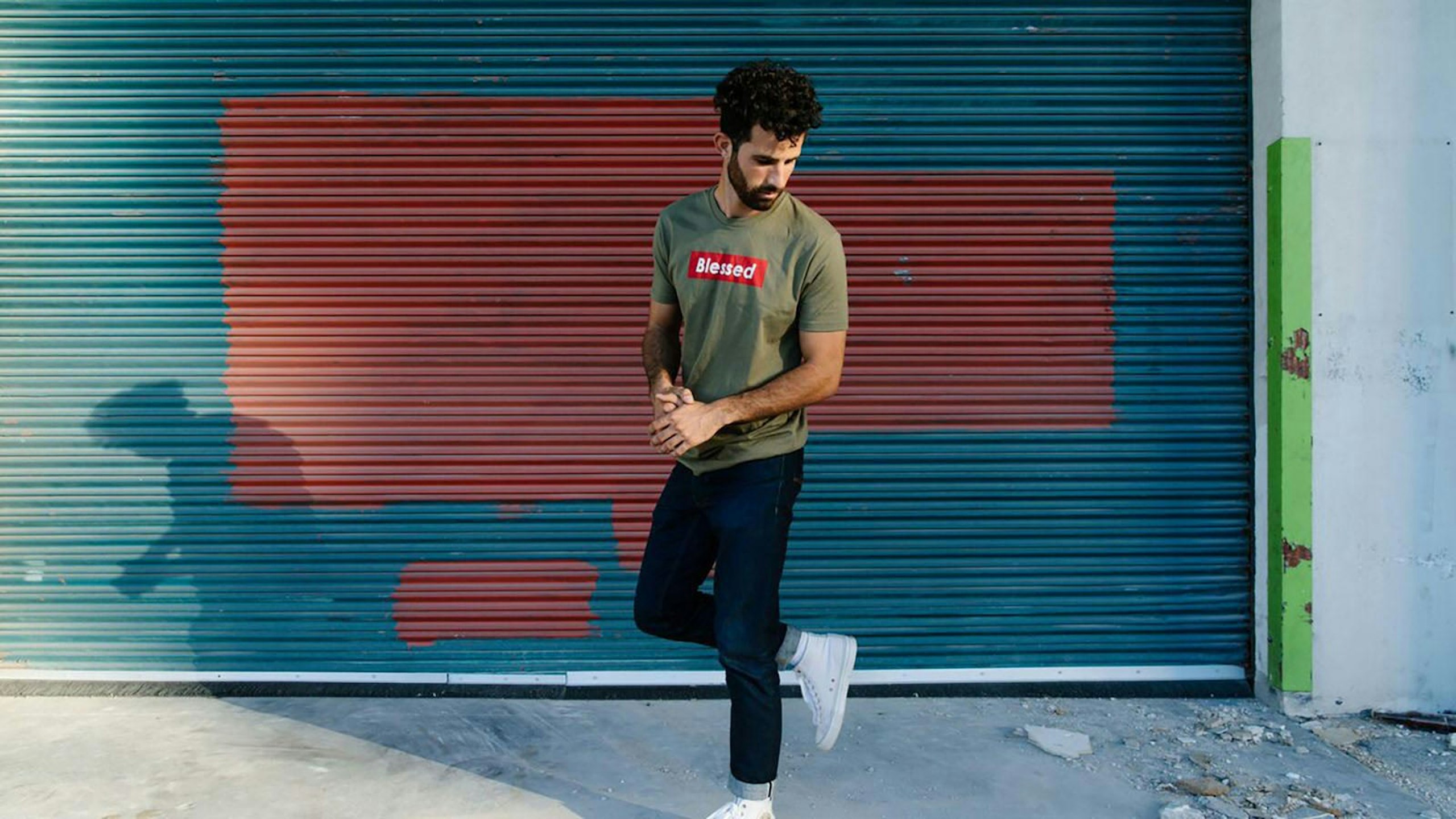 man wearing a green shirt in front of a garage 