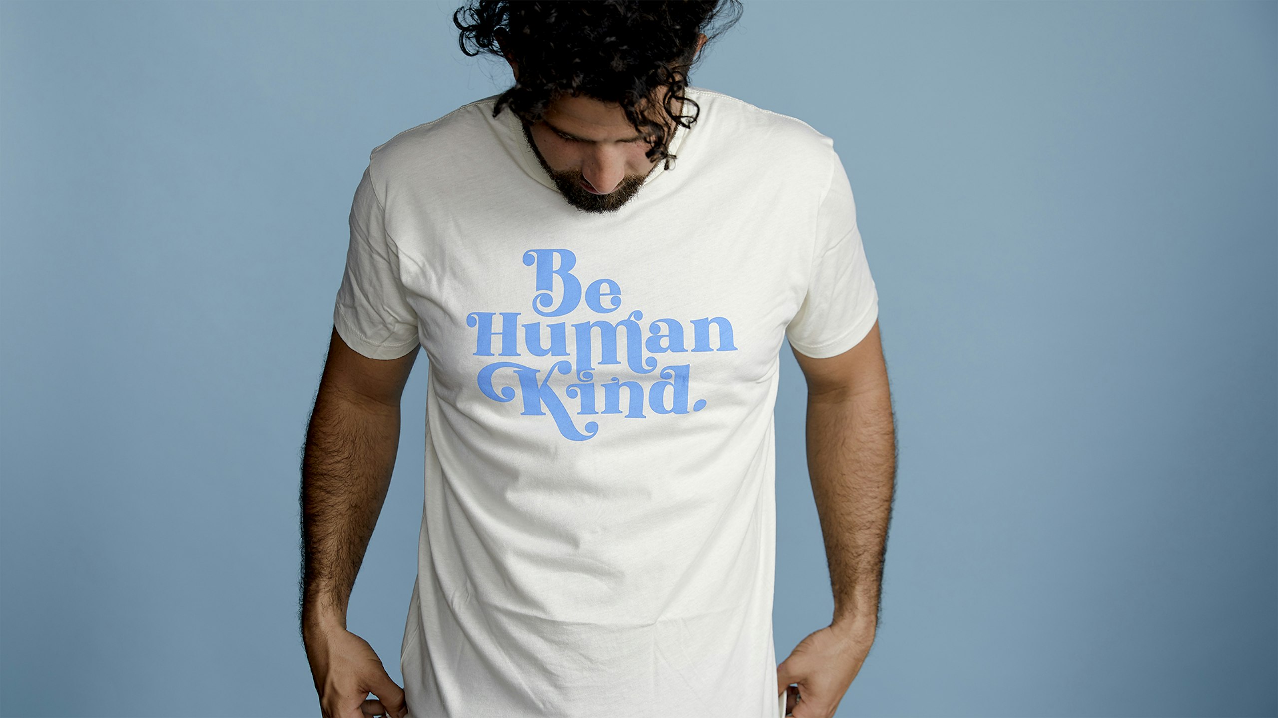 man wearing a white t-shirt with blue "be human kind" letters