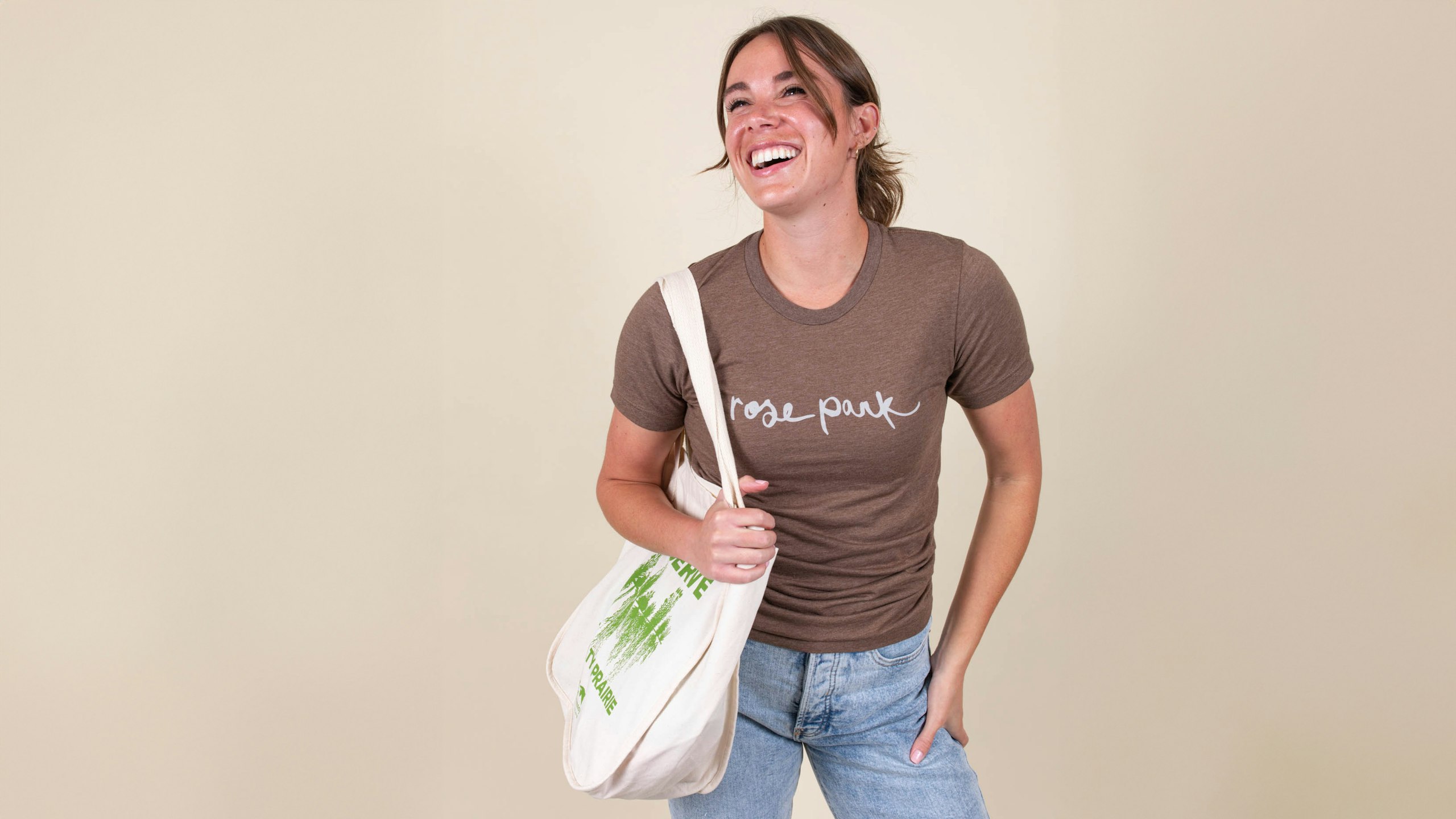 women wearing a brown t-shirt holding a white tote bag