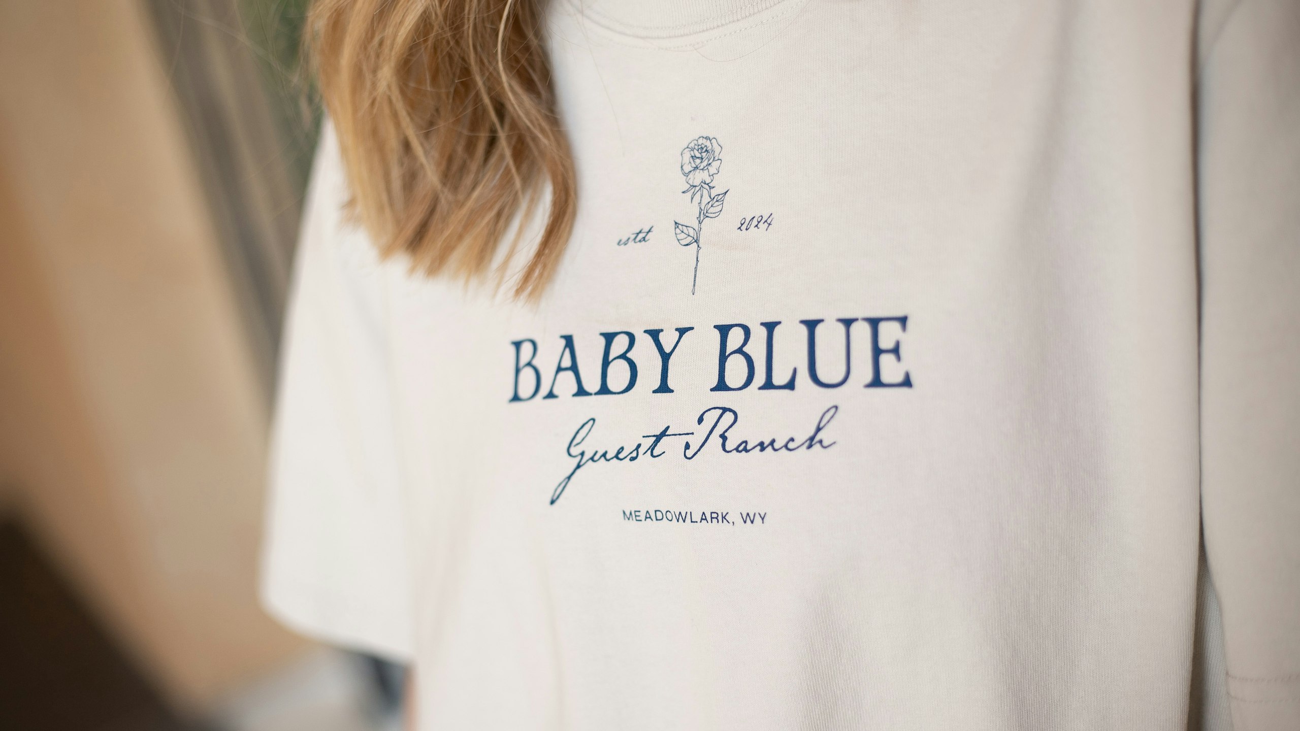 close-up on a white-cream t-shirt with baby blue logo printed in navy