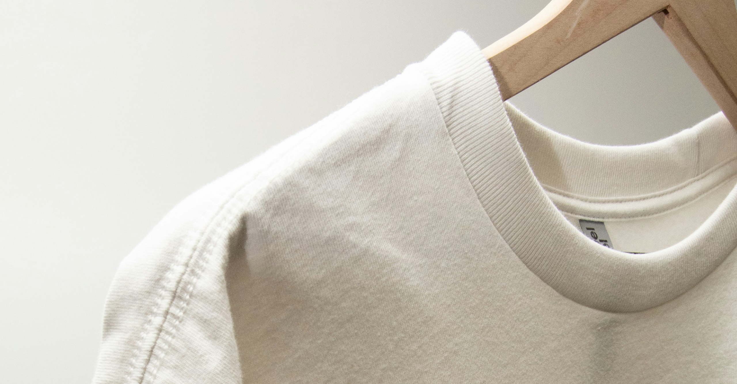 close-up to a white next level heavyweight hanging on a wood hanger
