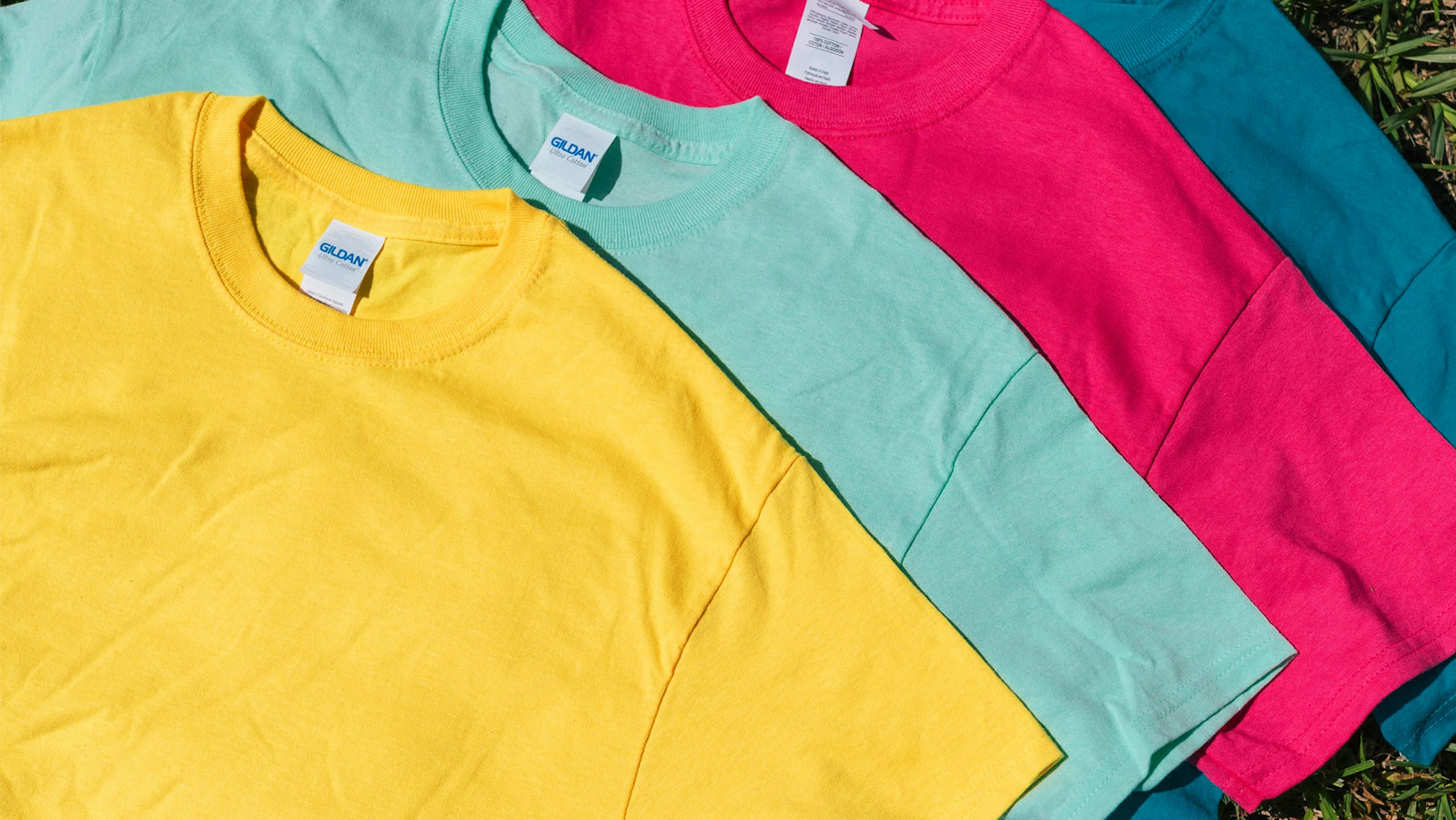 four t-shirts: one bright yellow, one bright green, one bright pink, and one bright blue