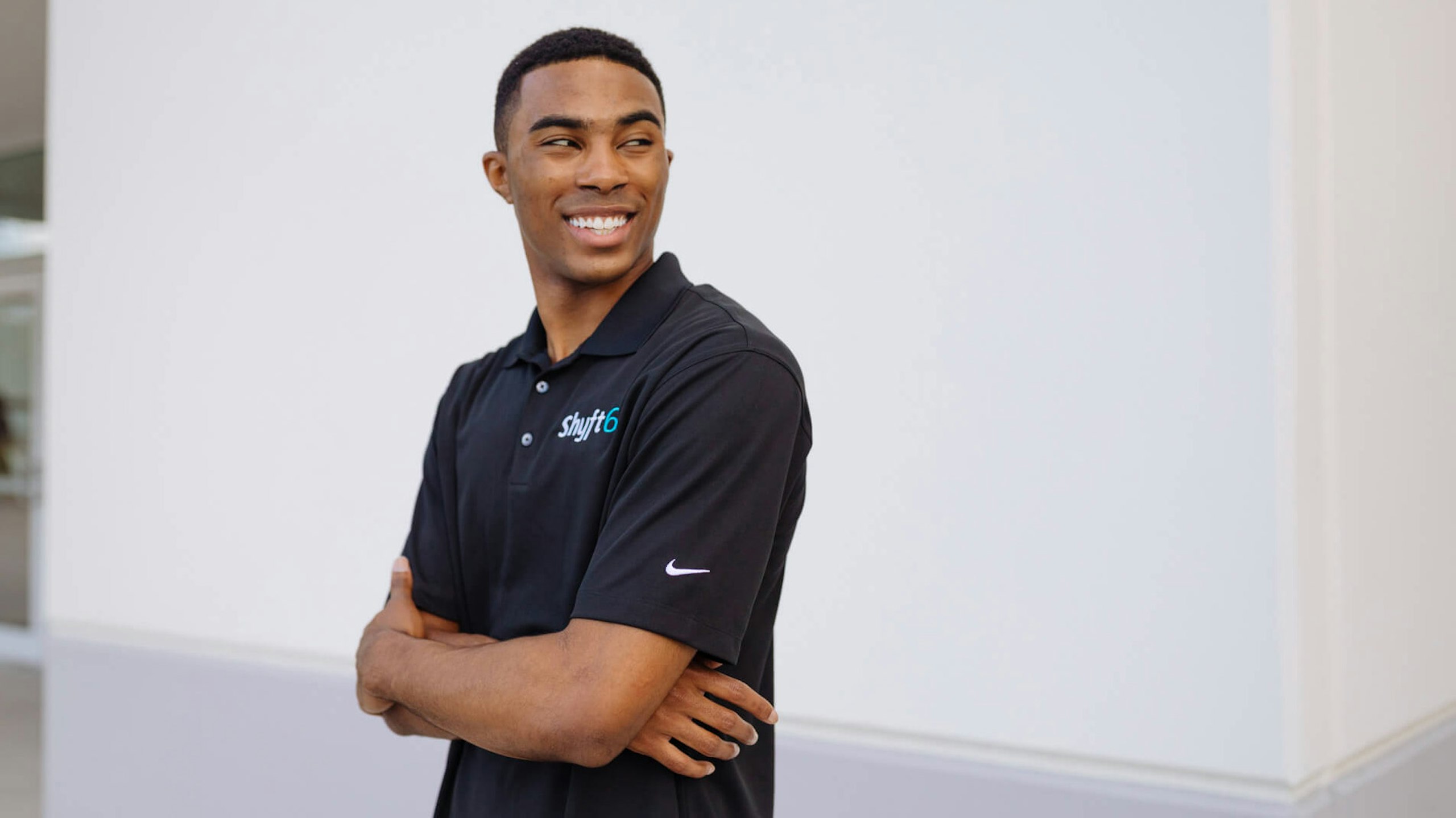 man wearing a black polo with shift 6 logo embroidered on the top right