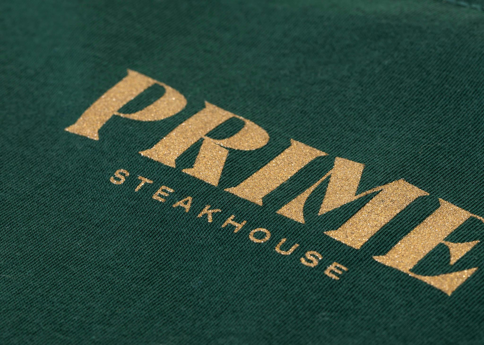 A green shirt with gold metallic ink that says "PRIME steakhouse" 