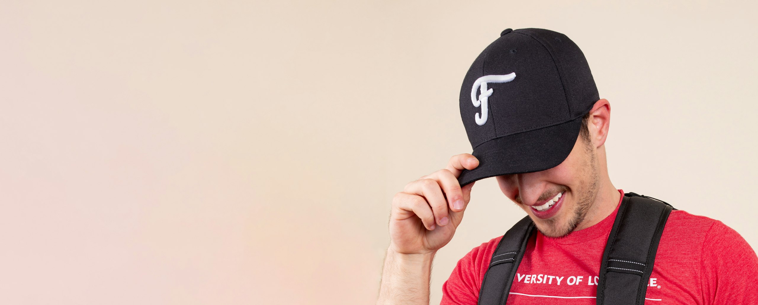 Man wears black hat with white puff embroidery of an "F" logo on it
