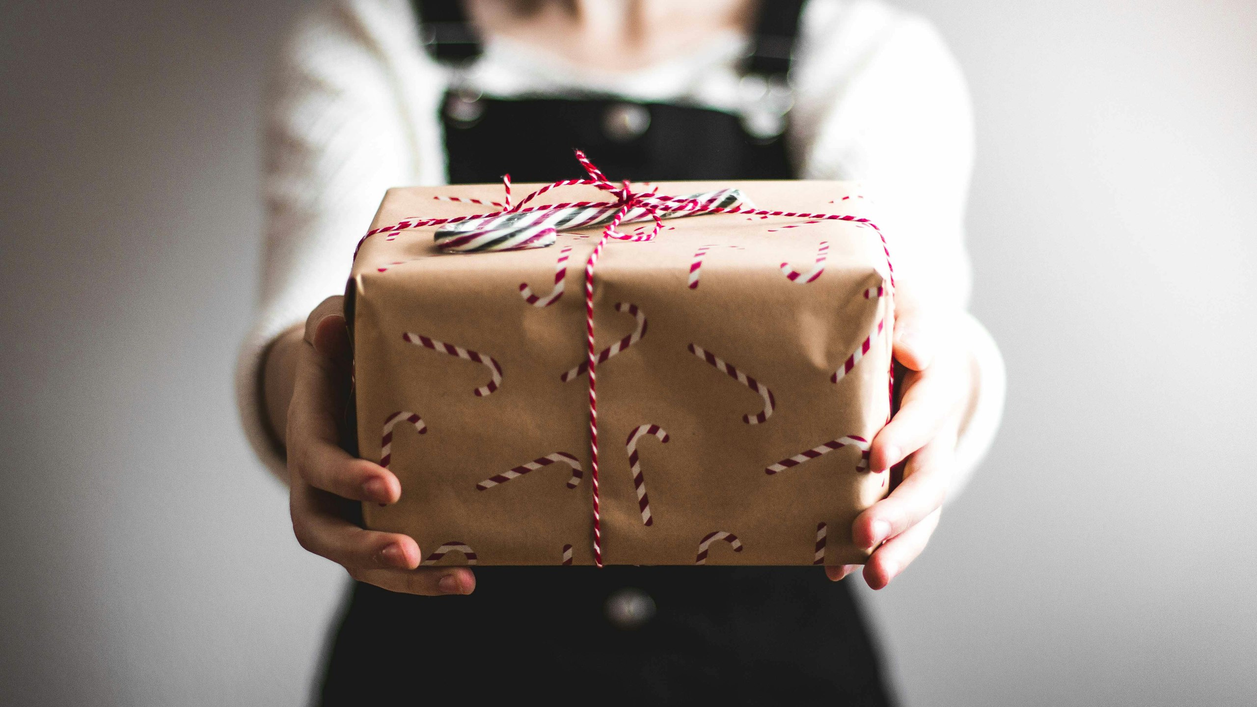 a person holding a holiday-wrapped package with candy canes