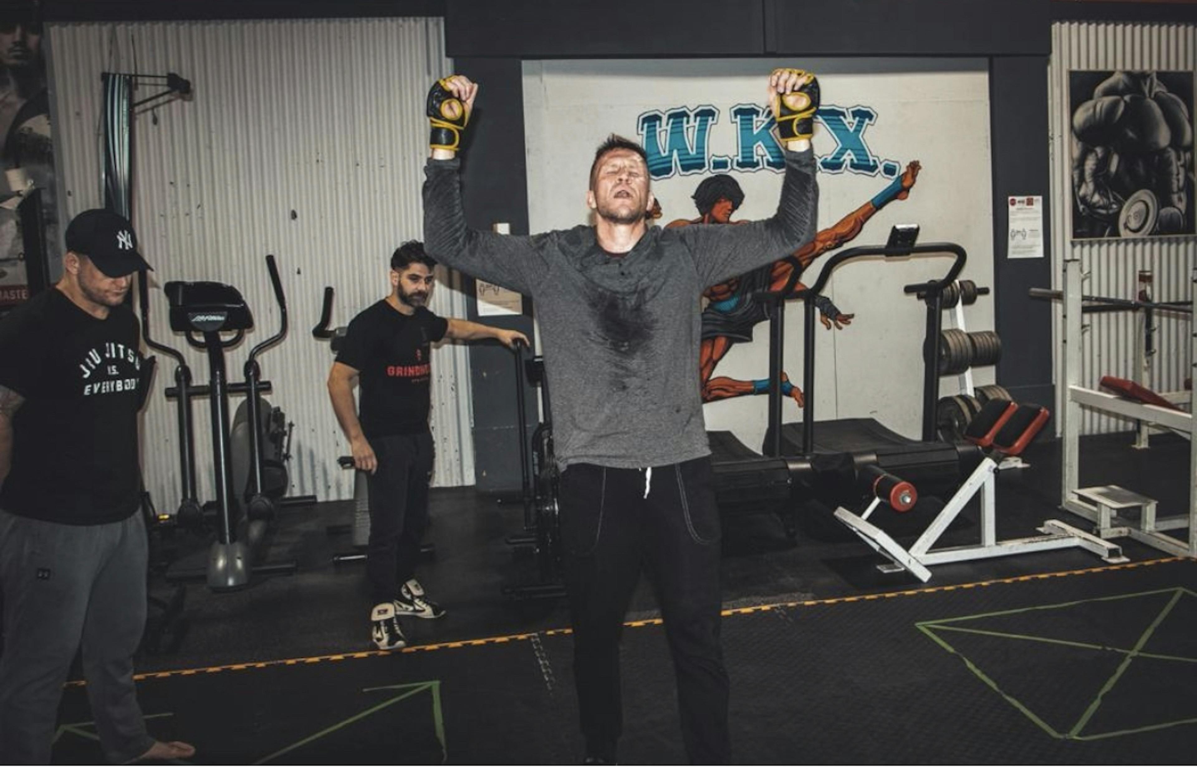 Jared holding his hands in the air in the middle of a grueling workout - he looks exhausted but triumphant