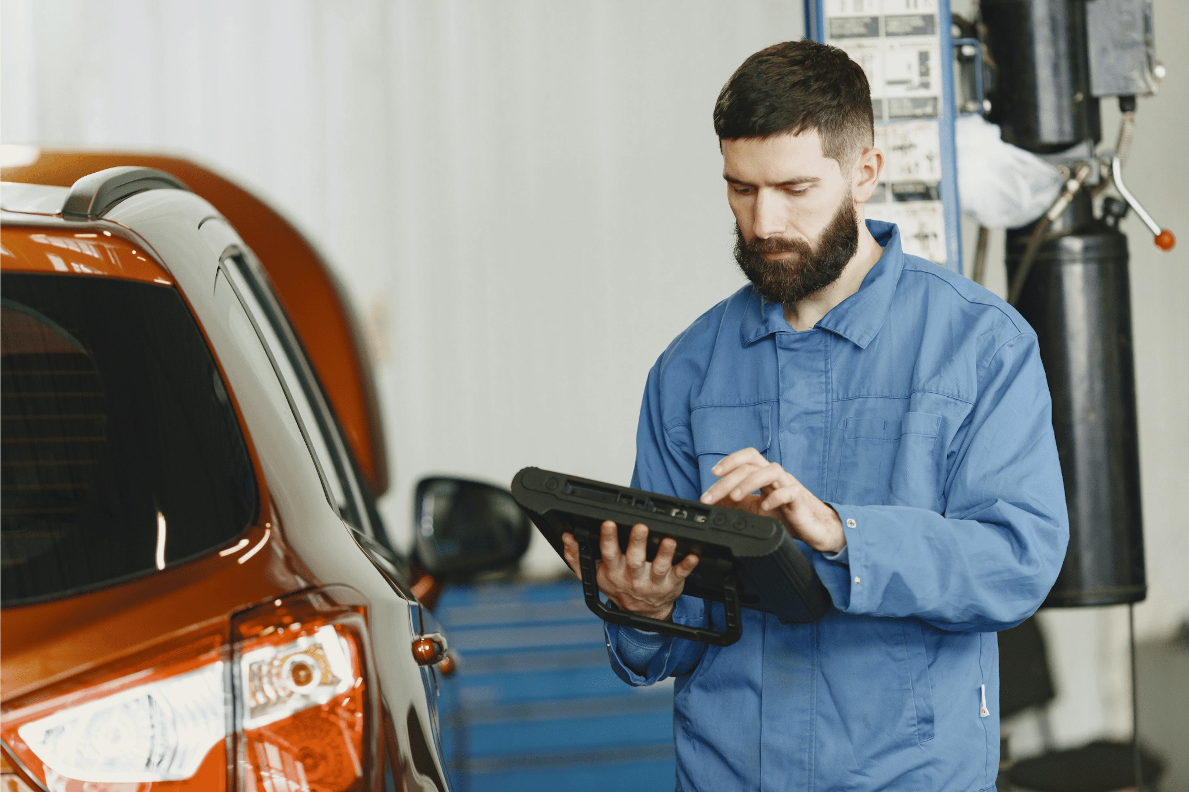 young mechanic checking the car in his right side through his tab