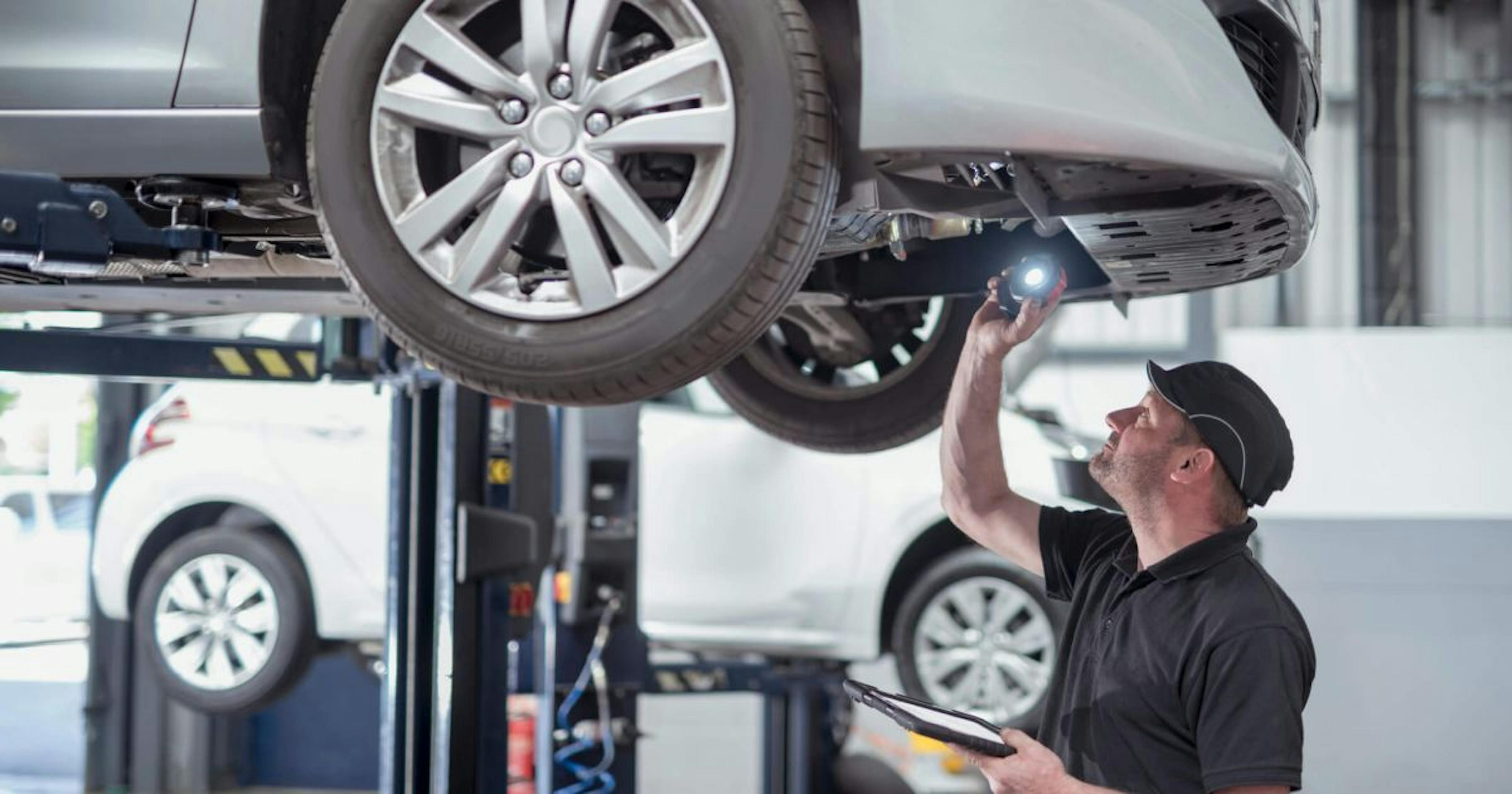 a mechanic checking the under chassis of a car