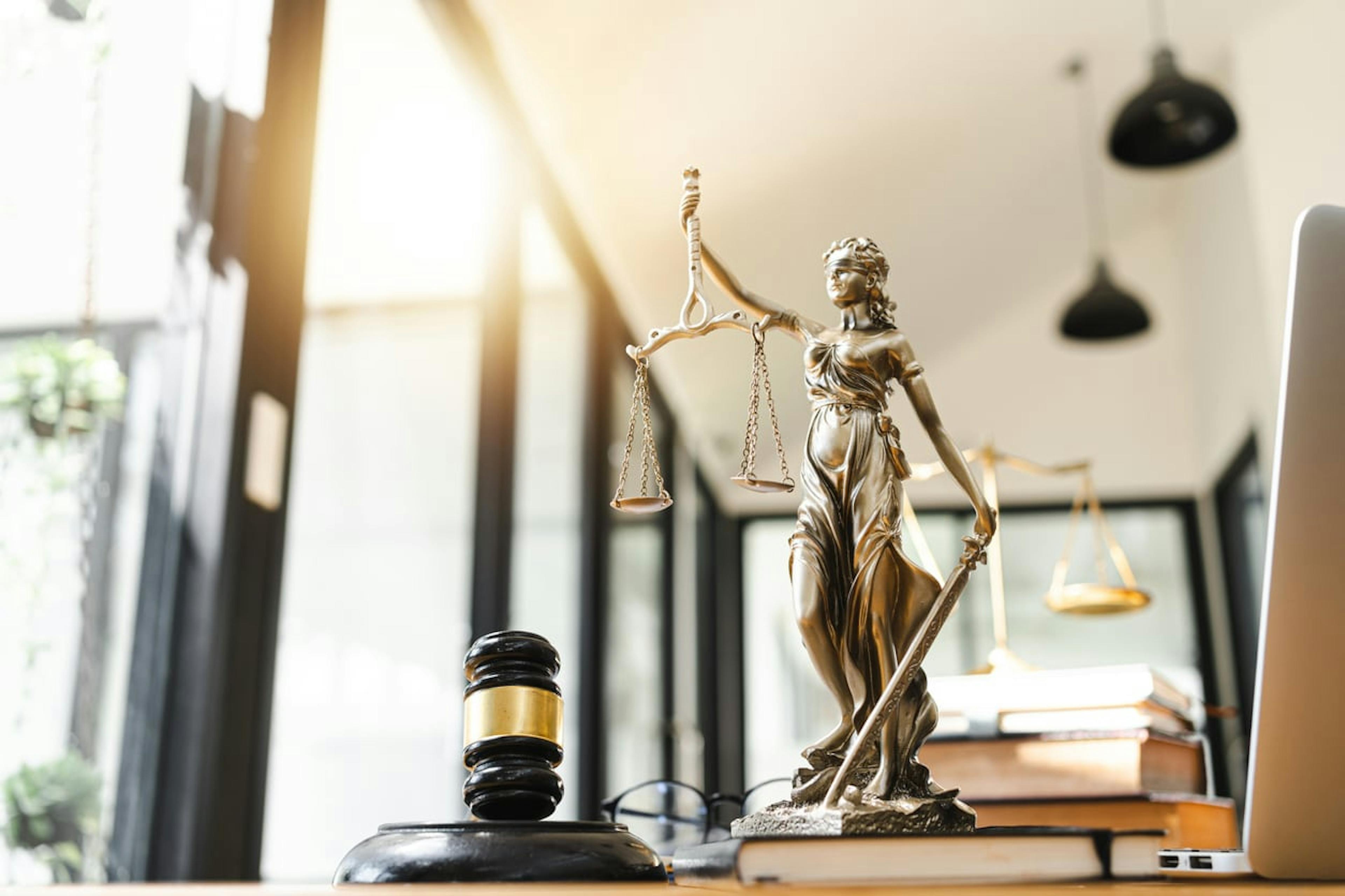 statue of justice besides a gavel on a desk