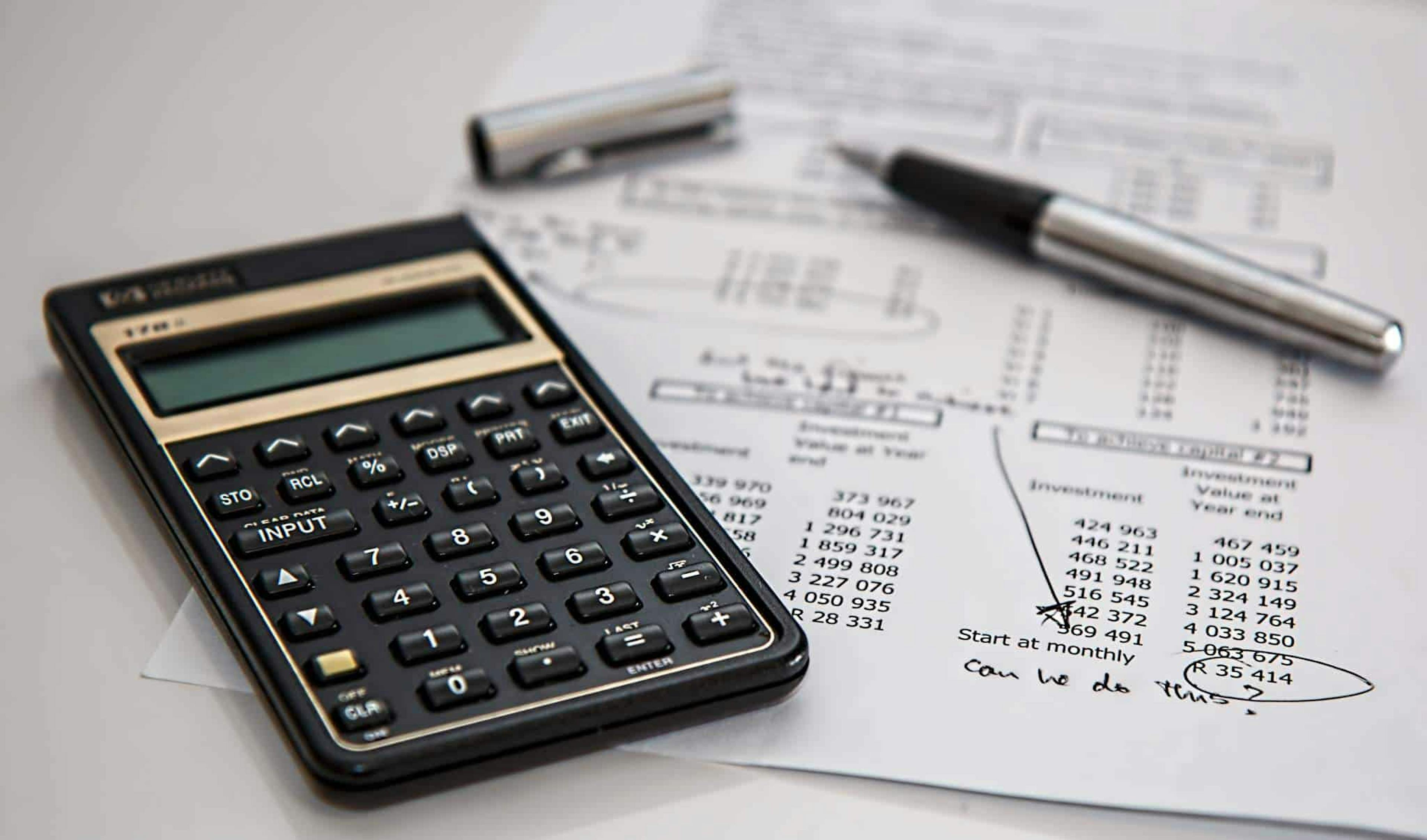 A calculator, a ballpen, and a document on a table