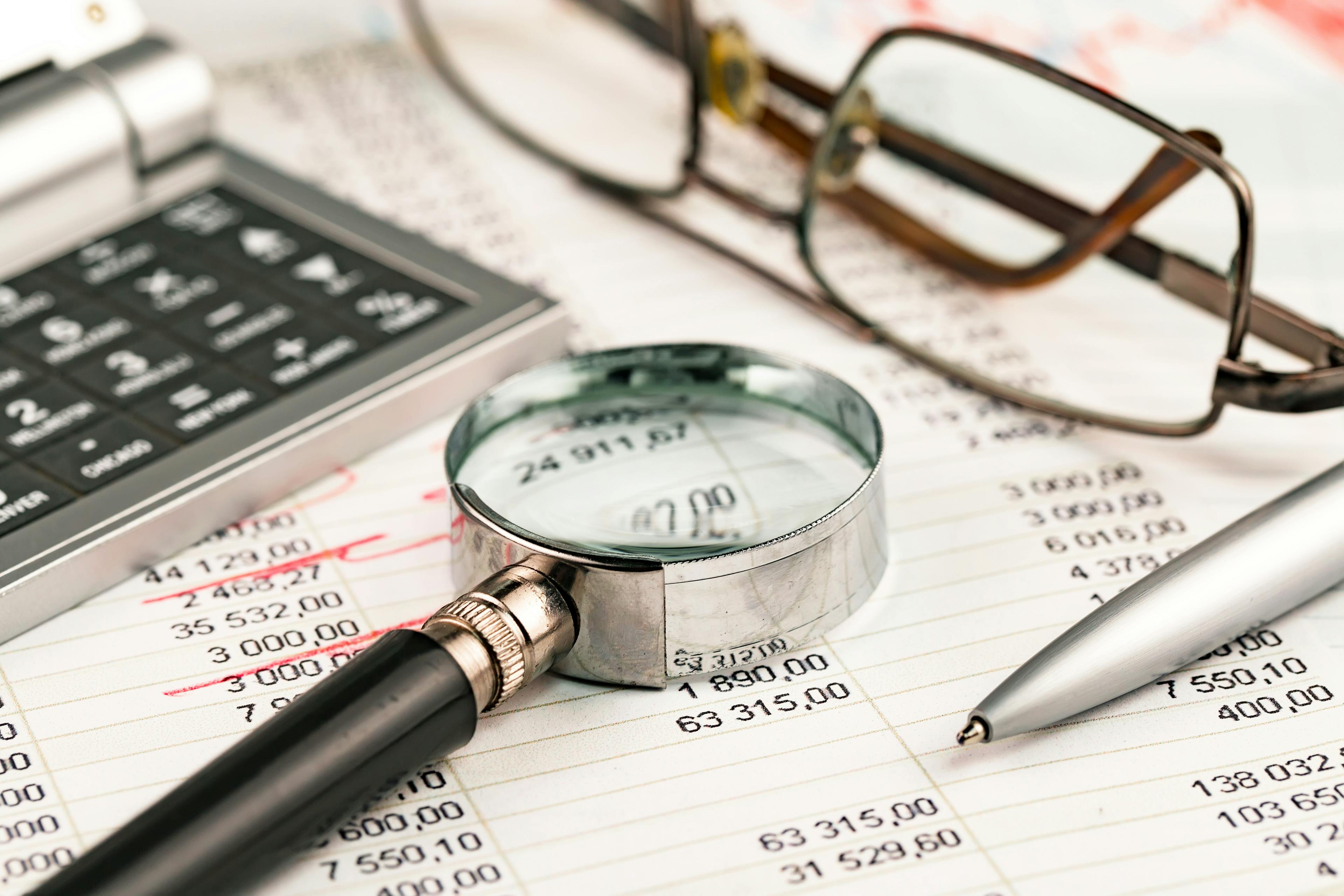 Magnifying glass over financial spreadsheet