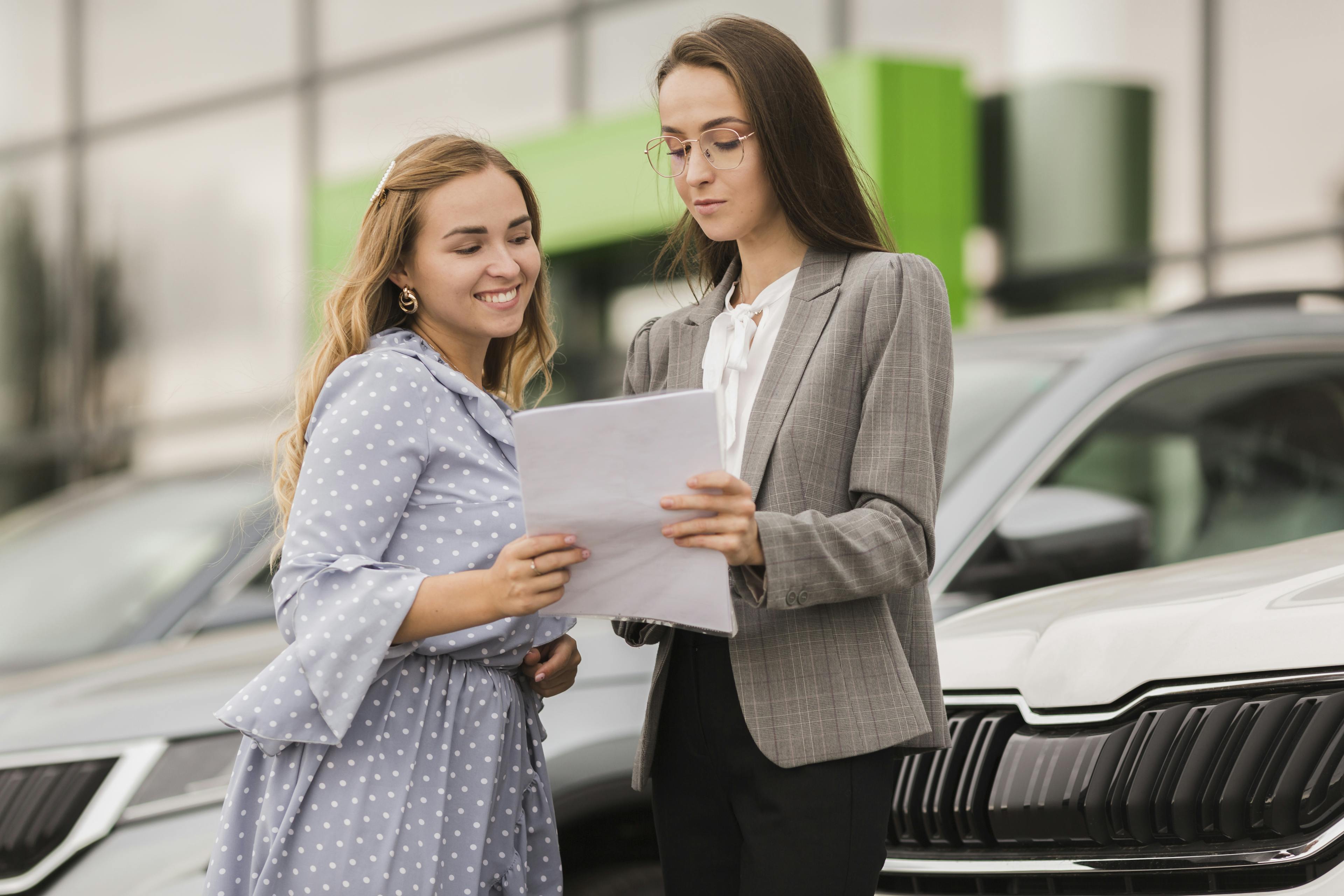 Two women discussing a contract about car finance refund