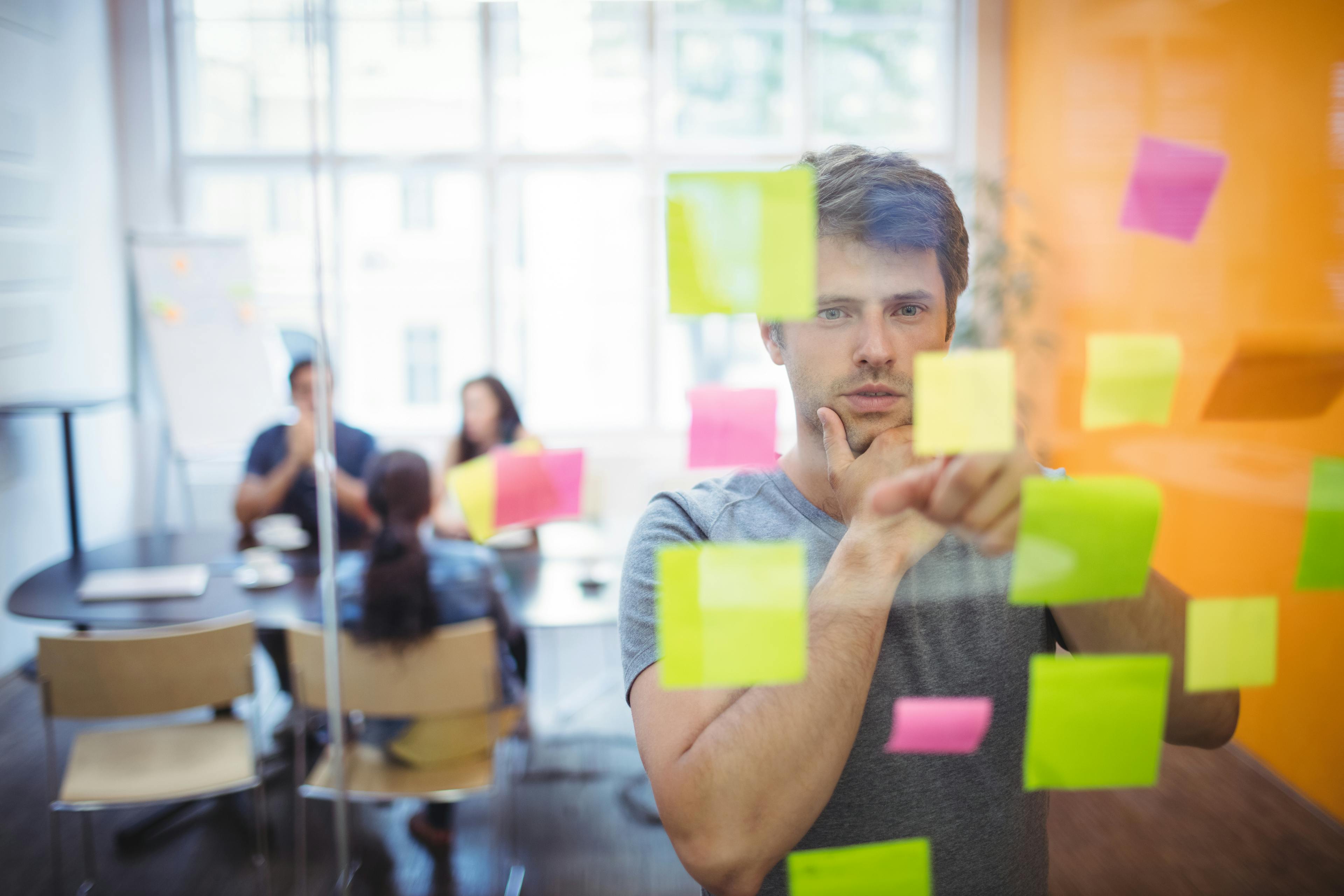 Man analyzing sticky notes on glass board