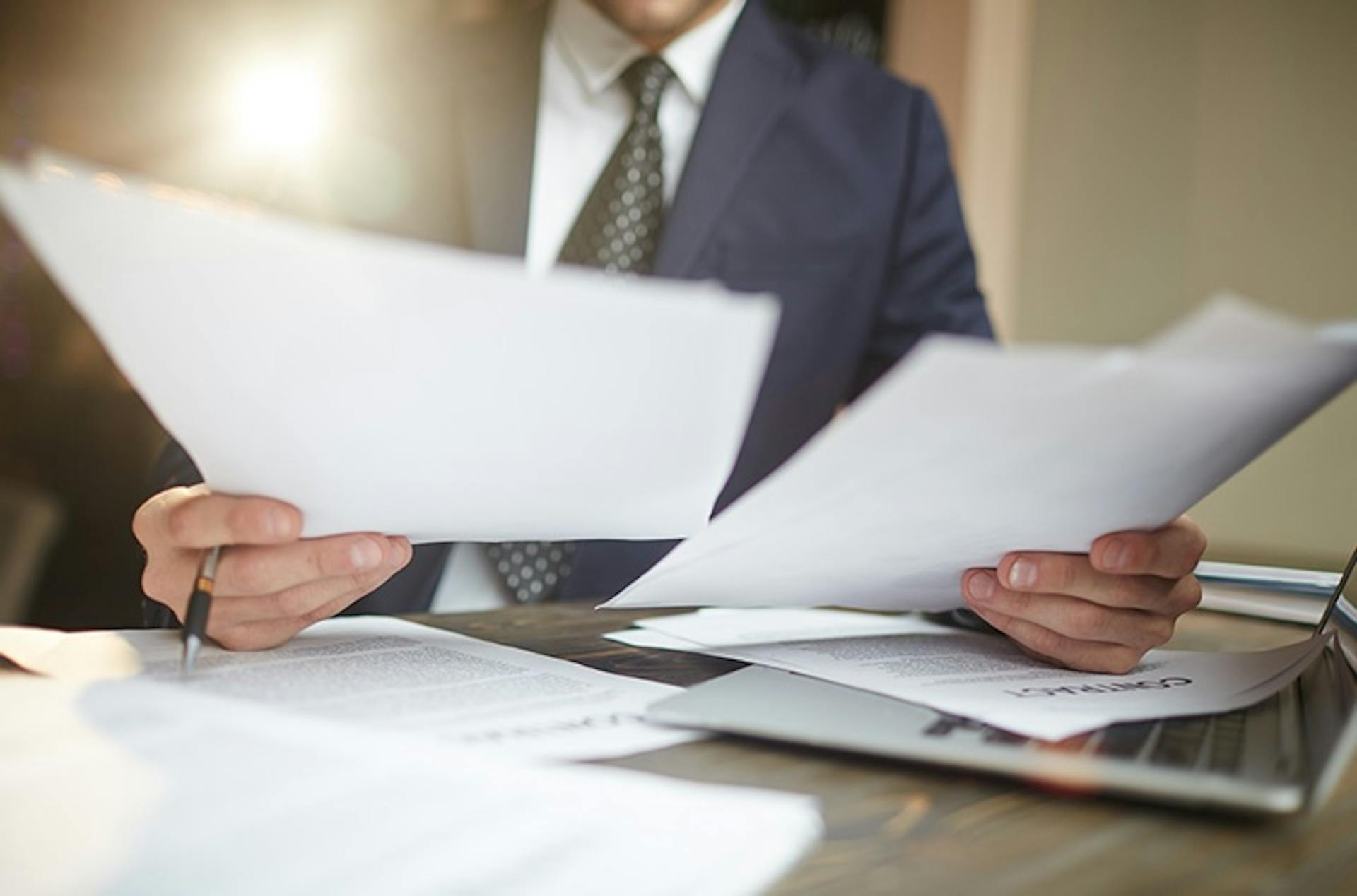 photo showing a businessman holding documents by hand on top of table