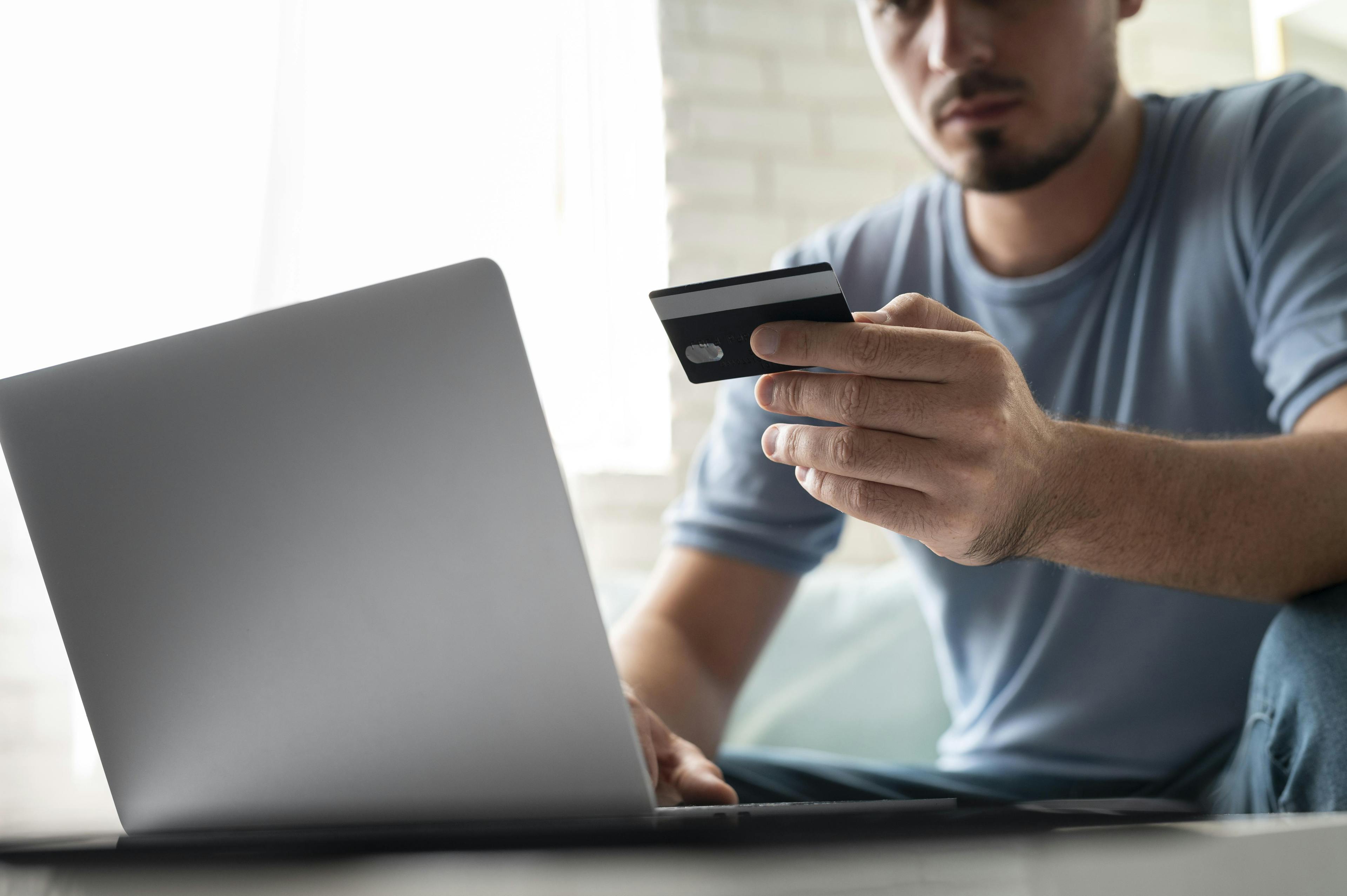 man looking in his laptop with his credit card