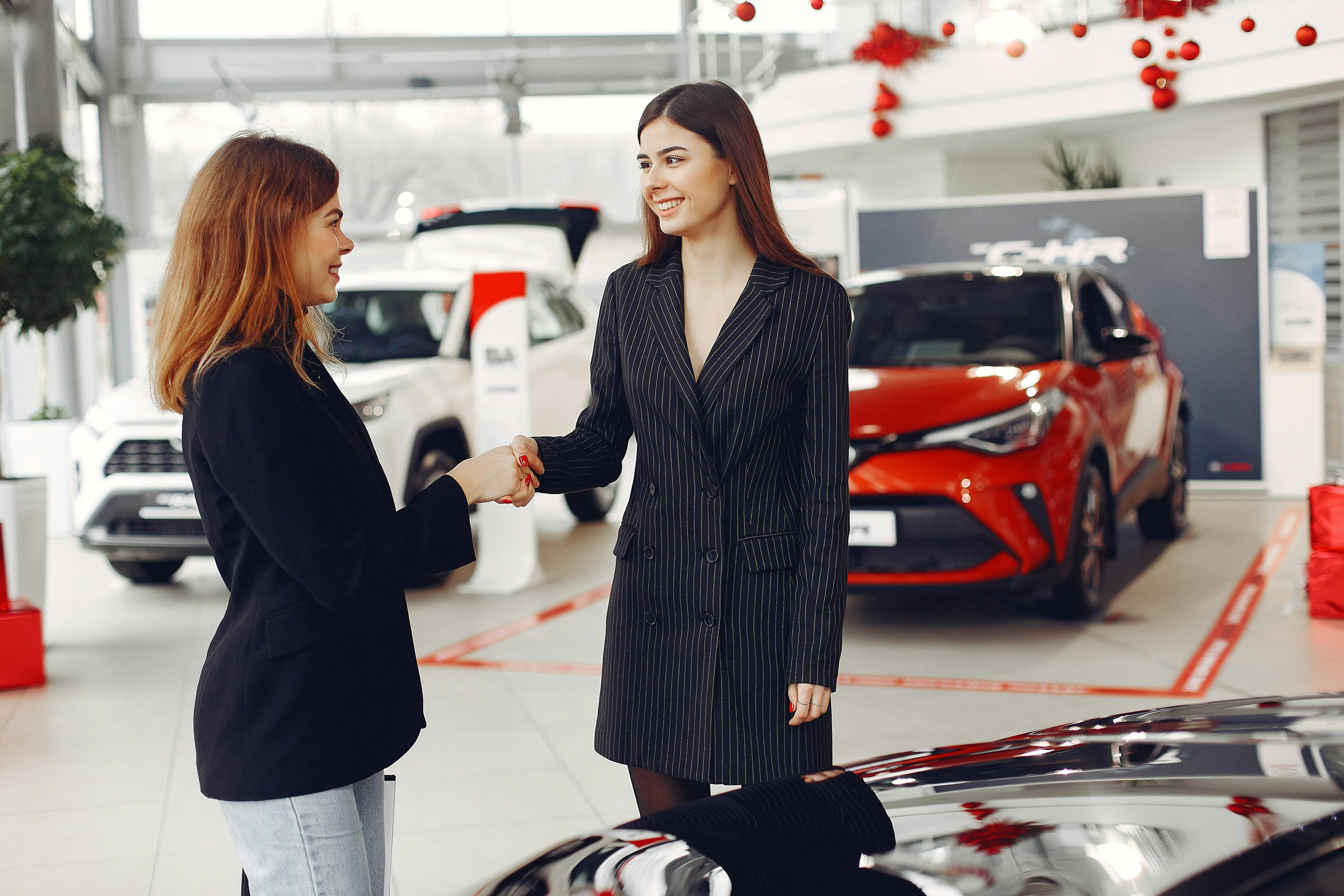 two women shaking hands after car dealership