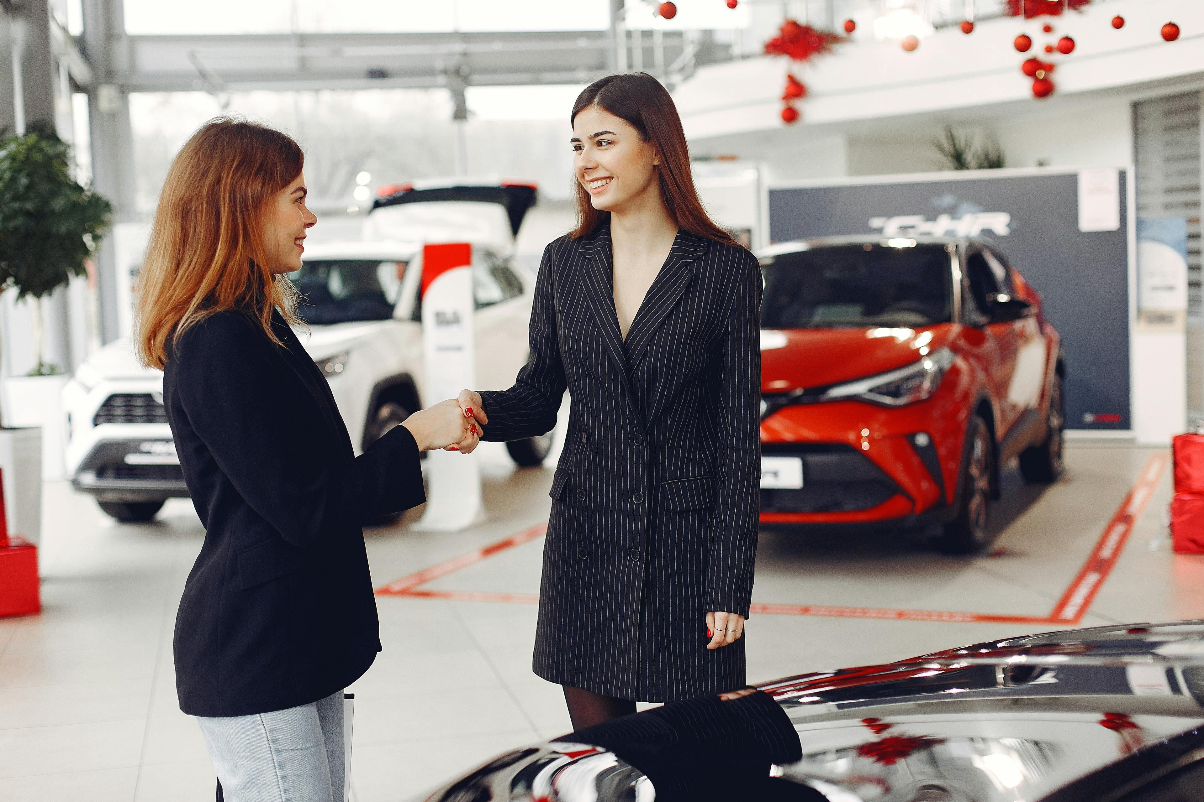 two women shaking hands after car dealership