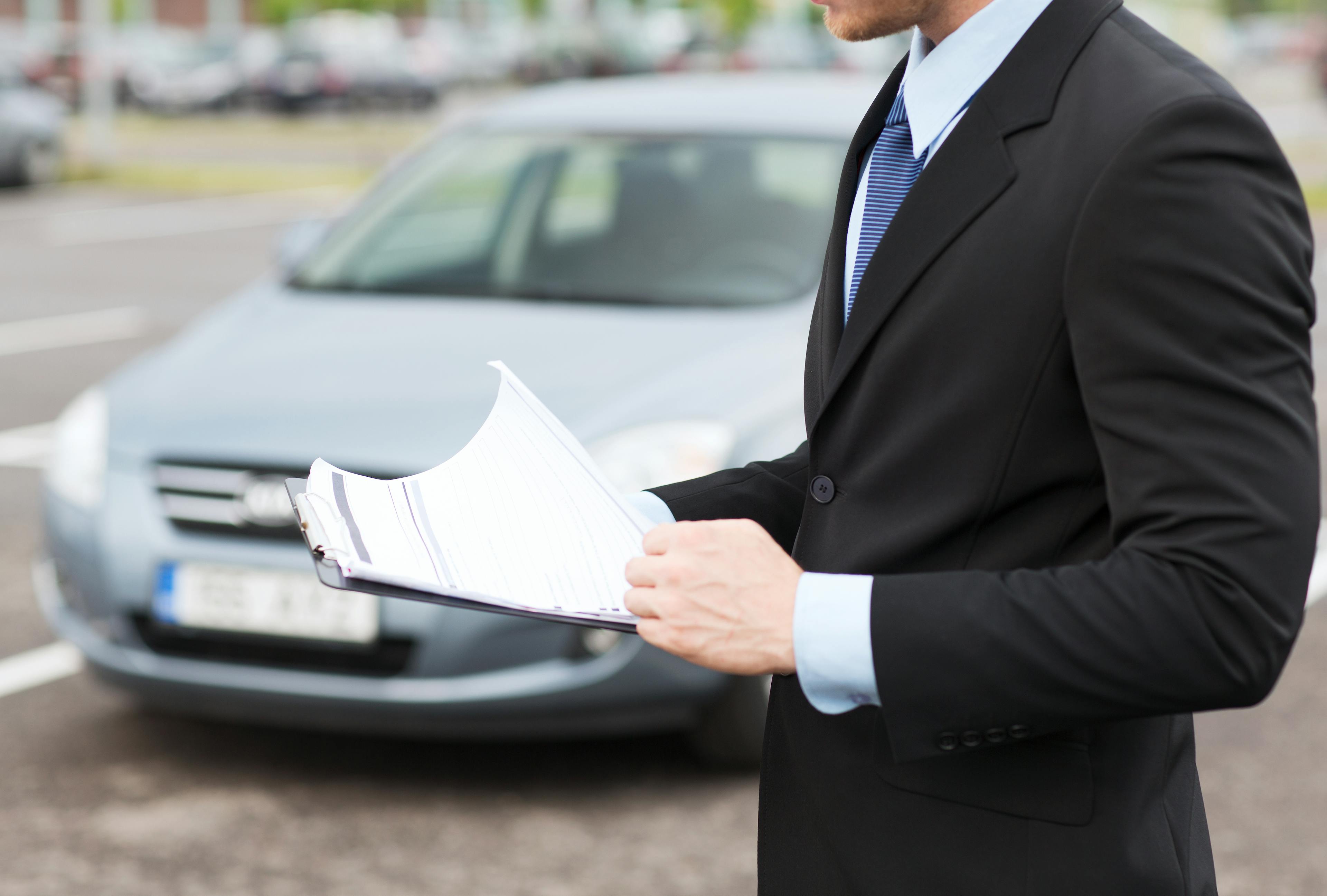 Man in suit holding car documents