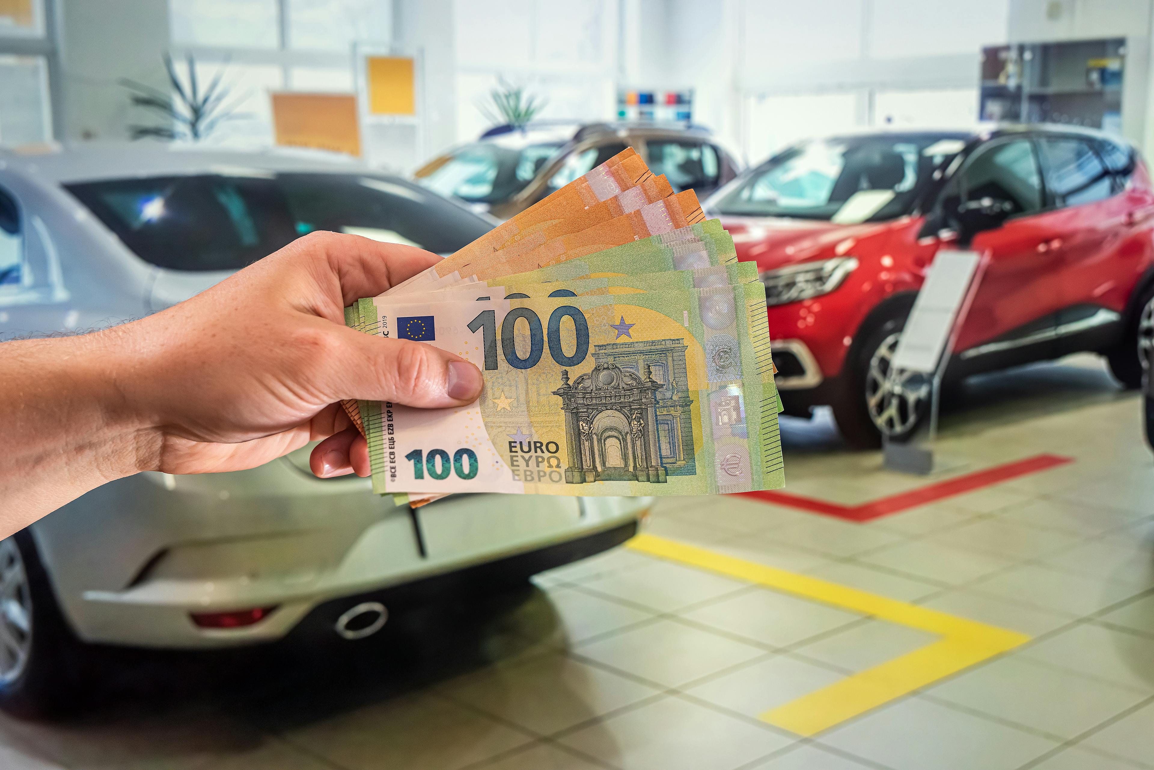 Hand holding euro cash in car dealership