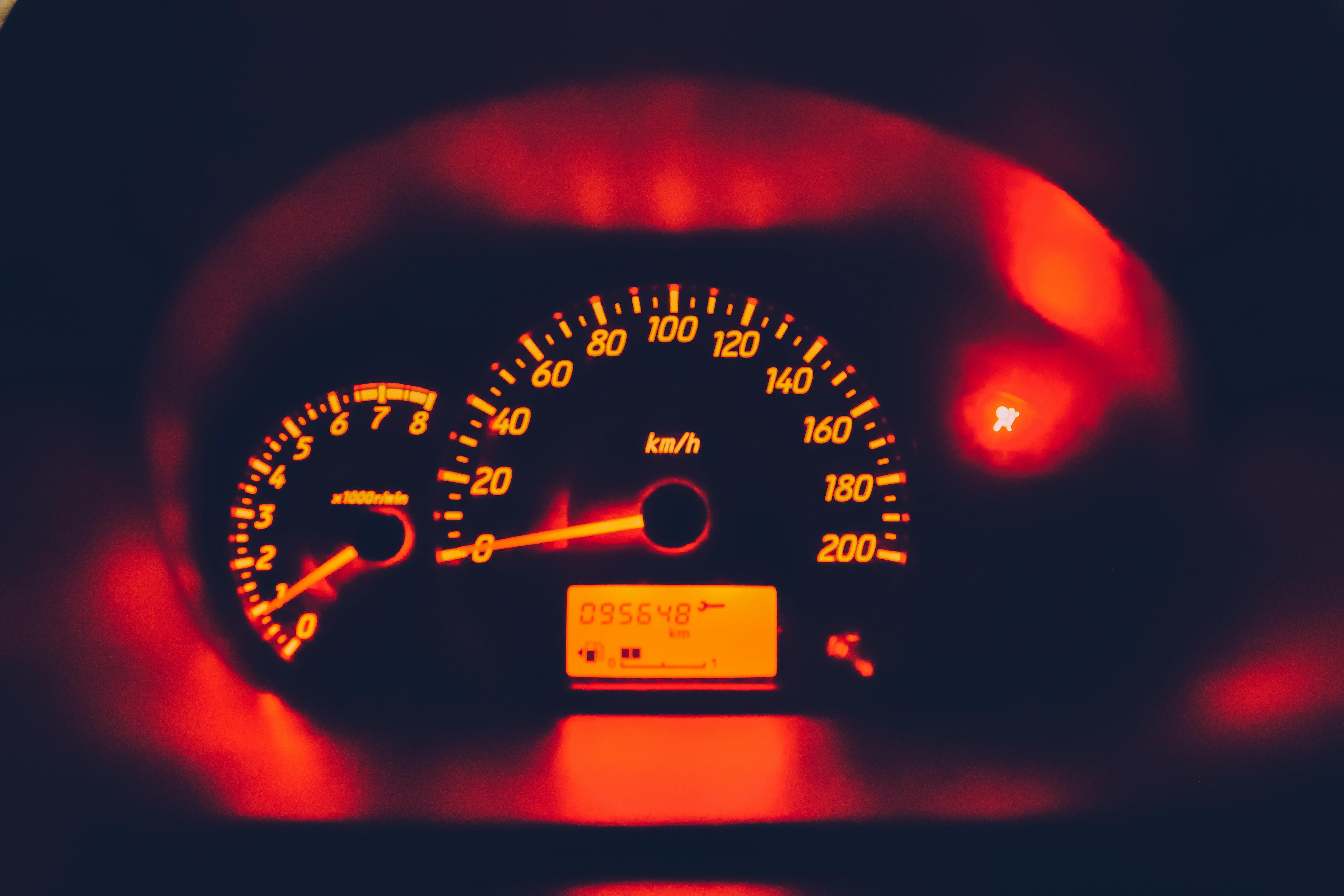 Red-lit car speedometer showing reached the Mileage Caps limit