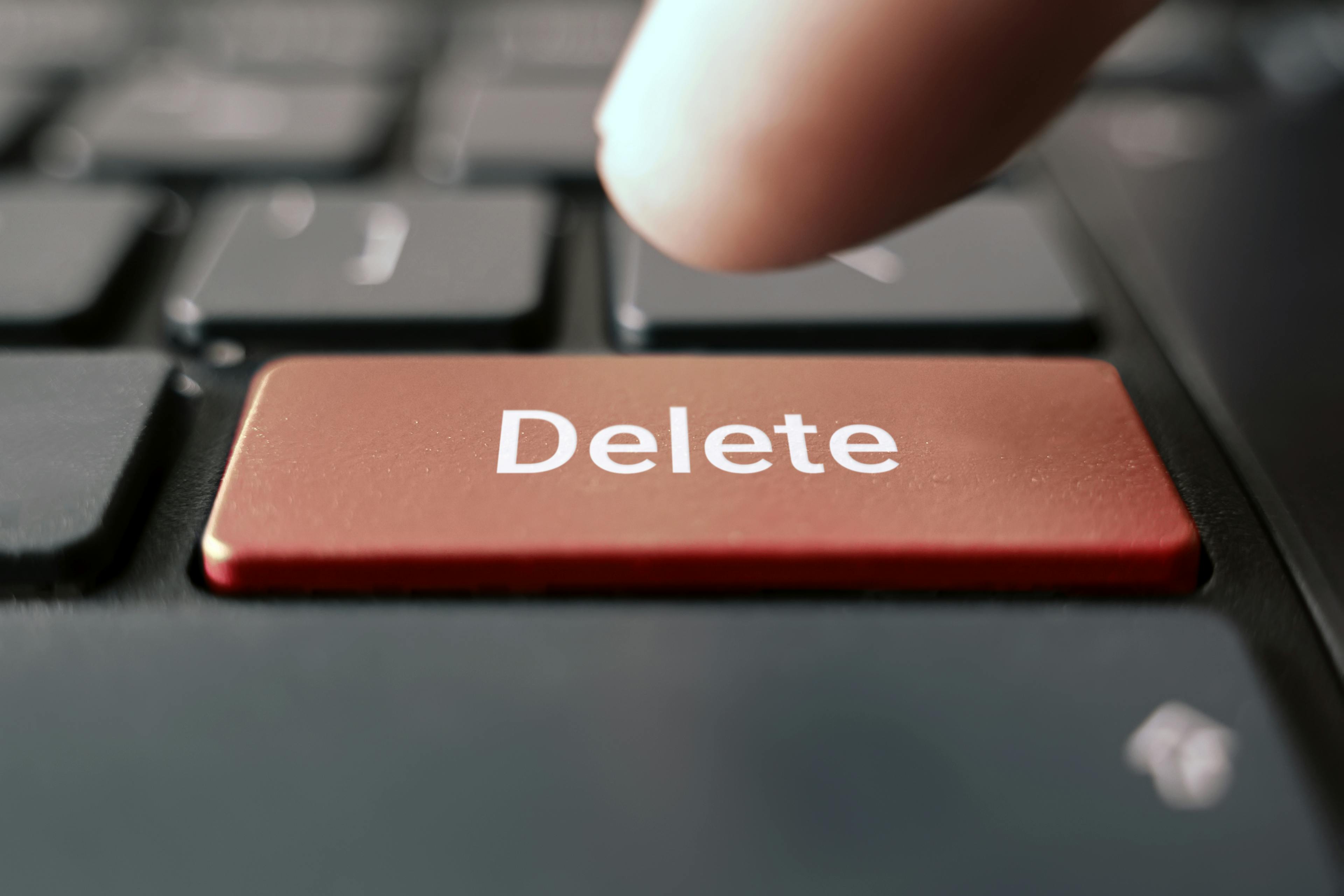 finger pressing red delete keyboard button