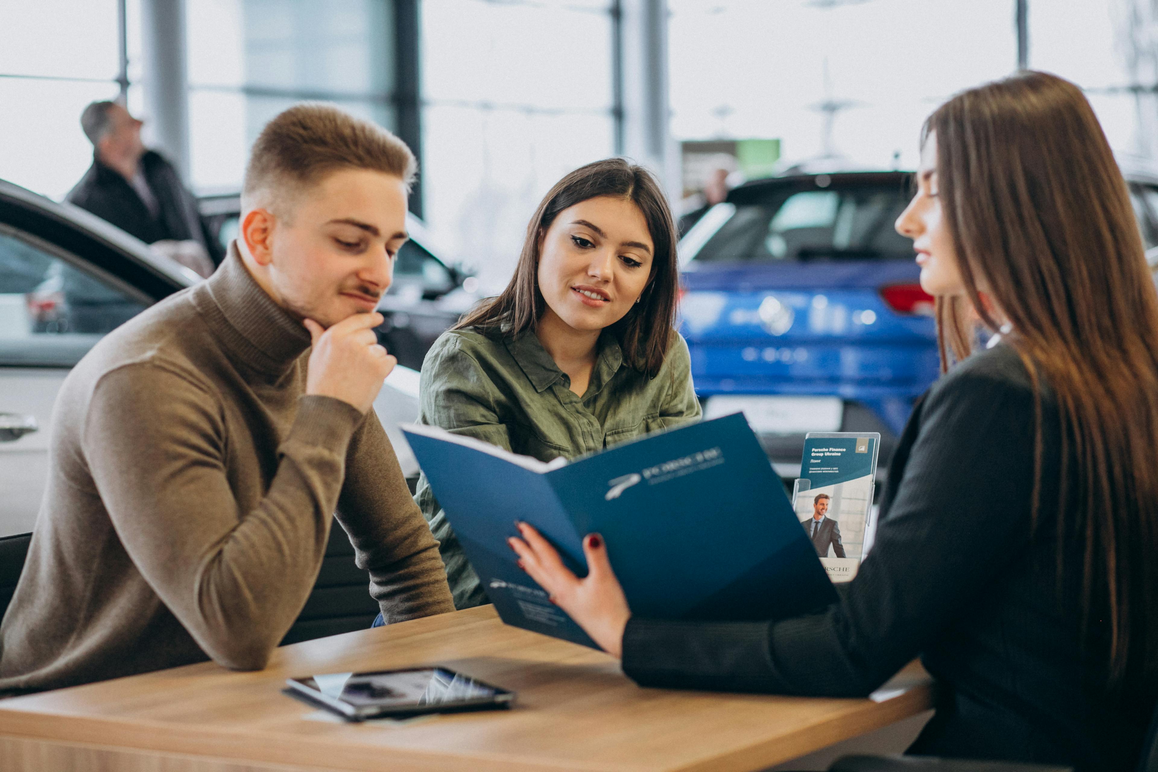 couple talking to a saleswoman in a car dealership