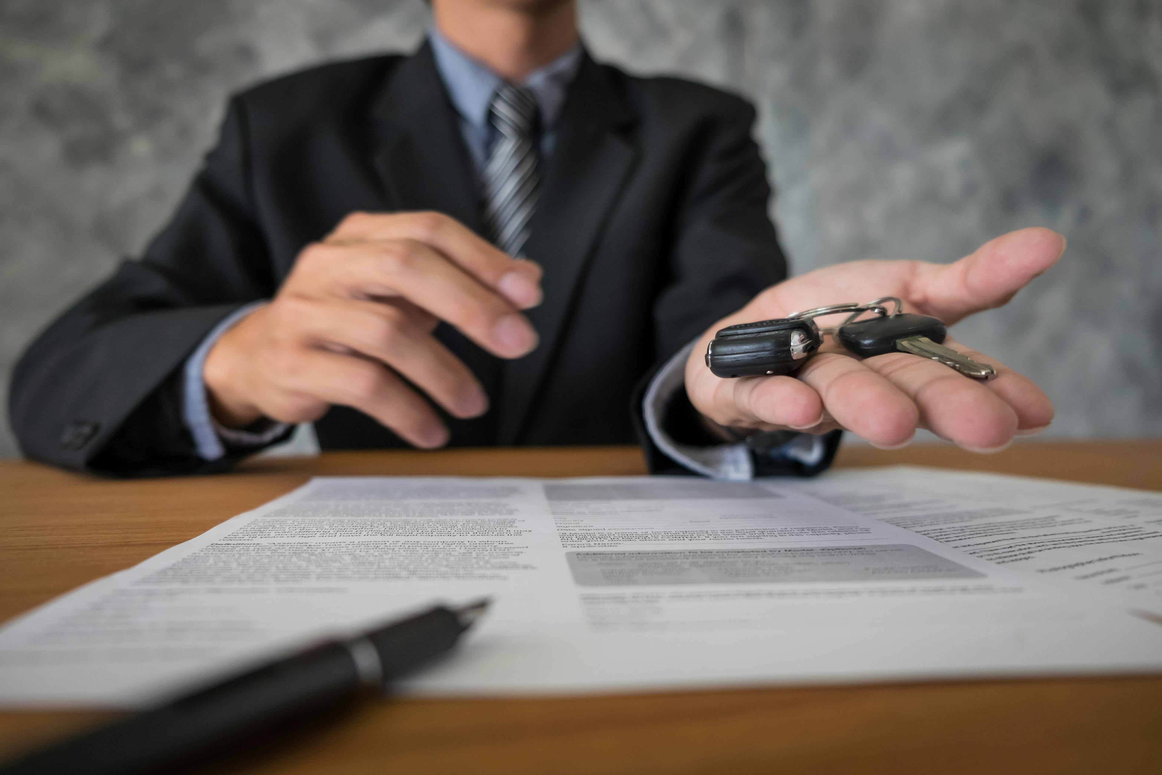 man holding car keys with contract and pen on the paper