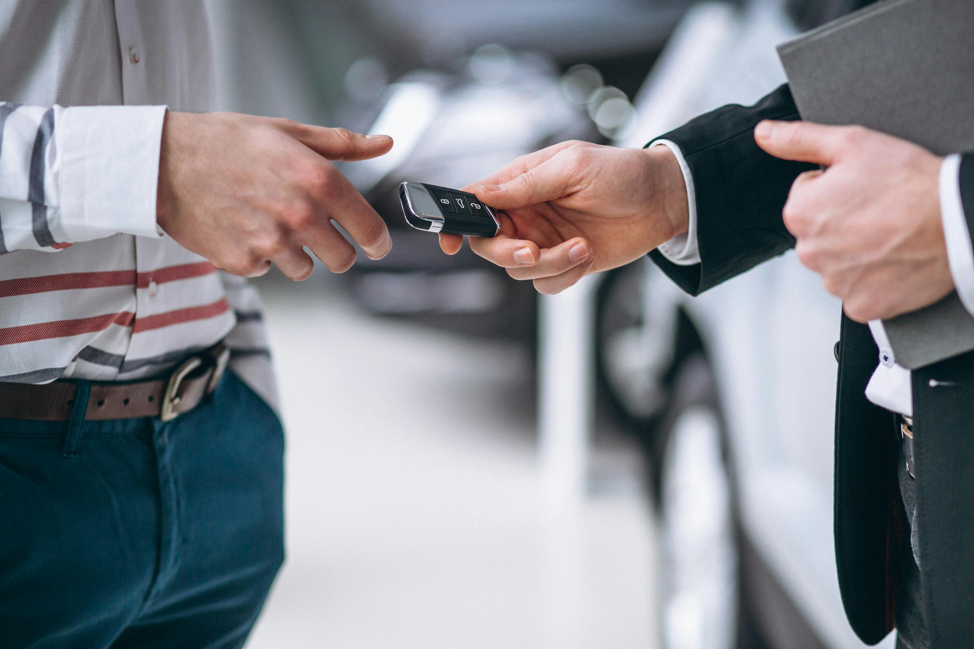 car salesperson handing car keys to a client