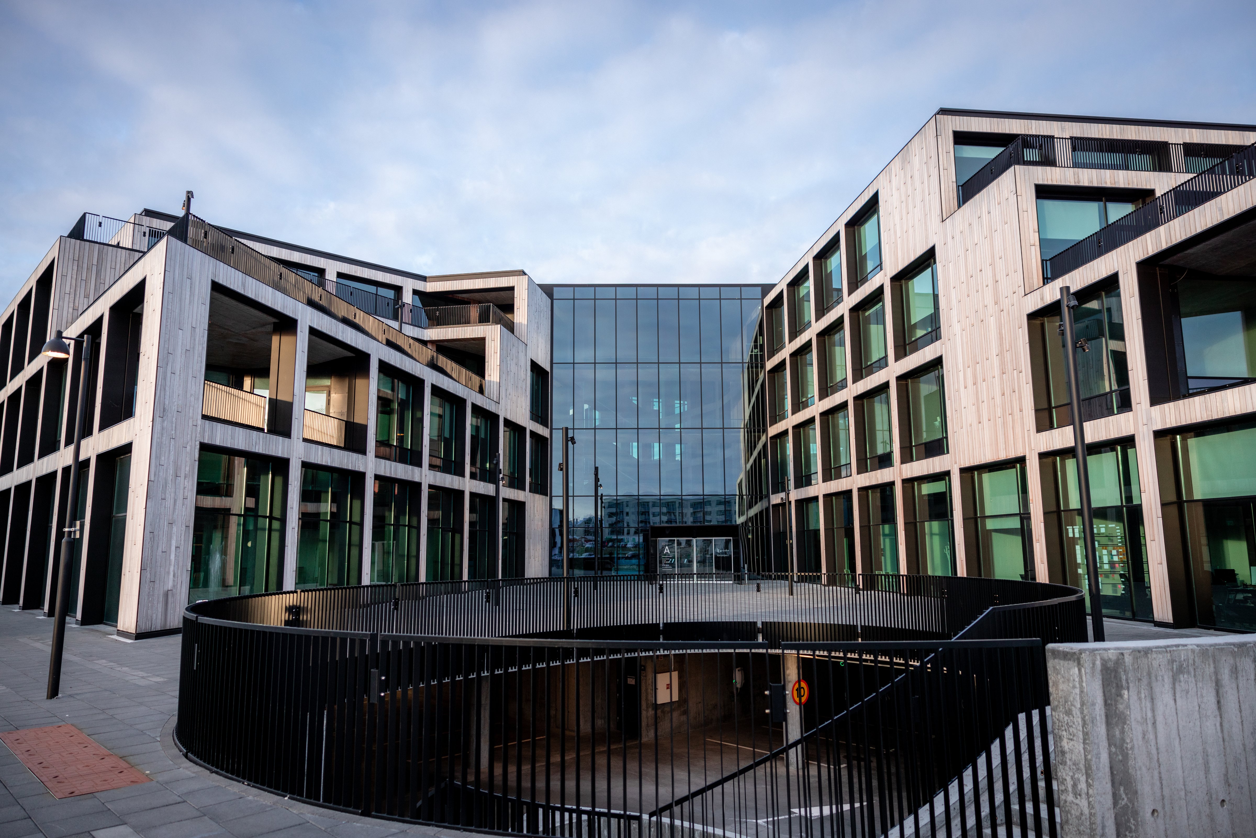 Exterior view of Gróska, a modern innovation and business center in Reykjavík, Iceland, featuring contemporary architecture with large glass windows and an open circular courtyard entrance.