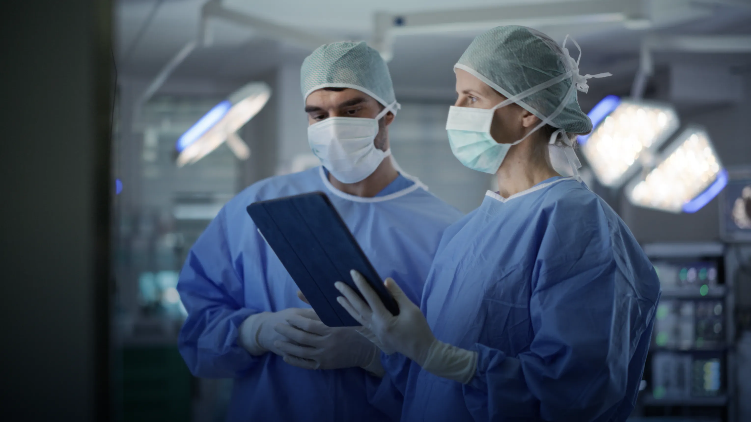 Two surgeons in scrubs reviewing a tablet in an operating room