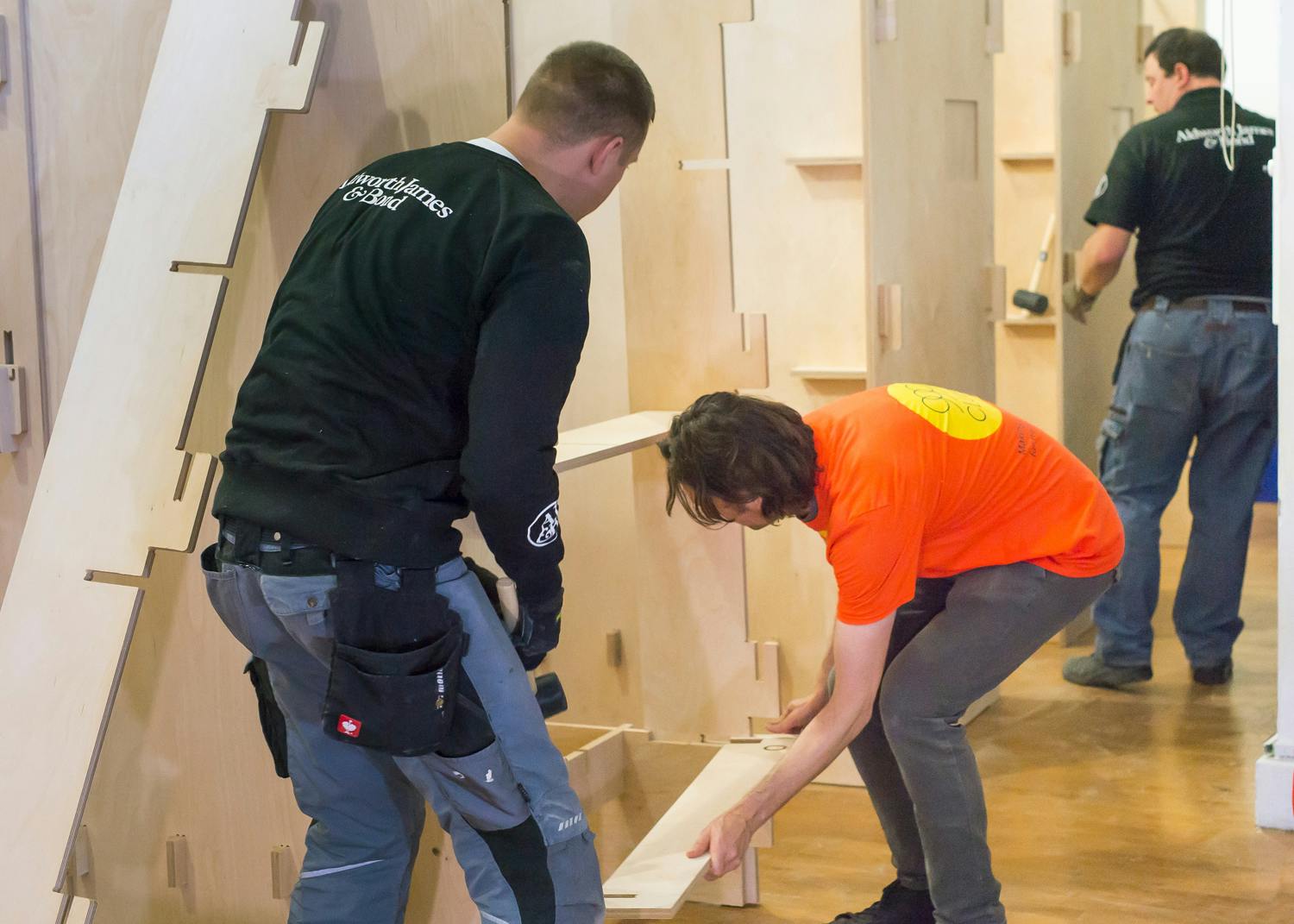 Photo of three people erecting a timber sleeping pod