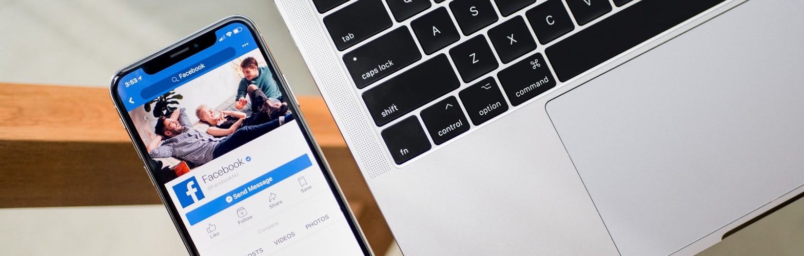 Facebook app opened in mobile next to laptop