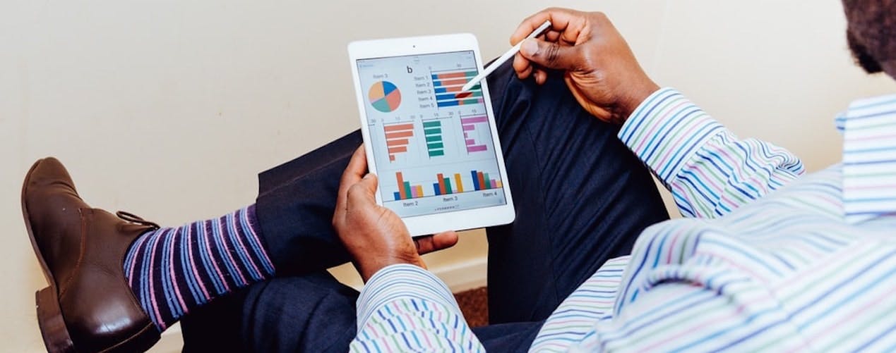 Man in striped shirt looking at statistics on tablet