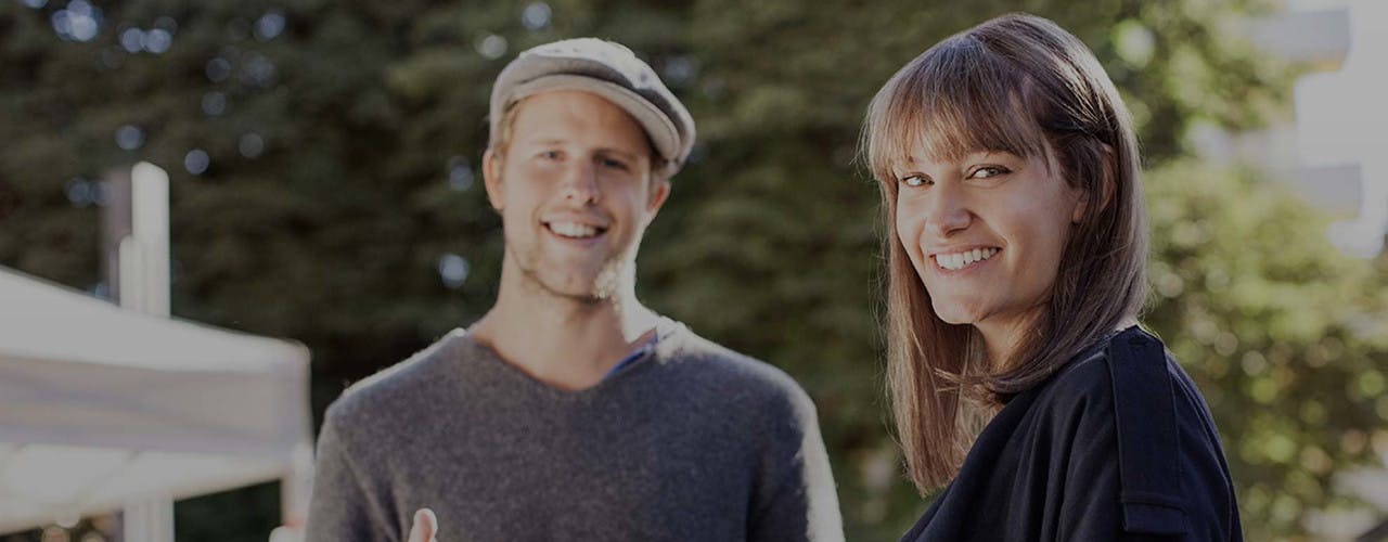 A young woman and man smiling and looking into the camera