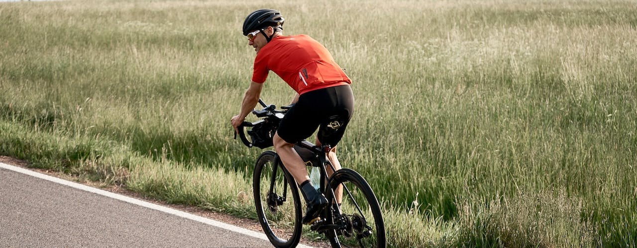 Road cyclist biking along a field