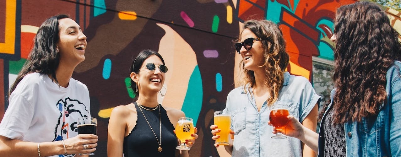 Women smiling and having a drink at festival